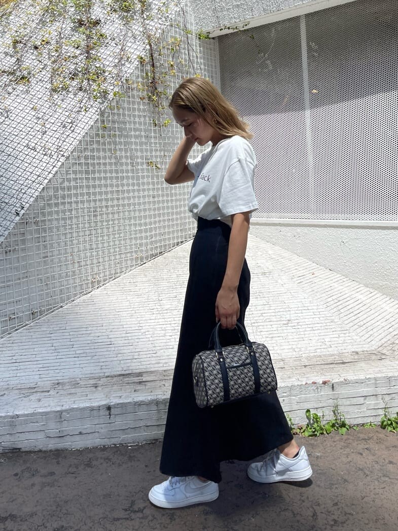 ブラック系のスカート、ブラック系のボストンバッグ、ホワイト系のTシャツ/カットソーを着用したレディースの夏コーディネートの3枚目の写真
