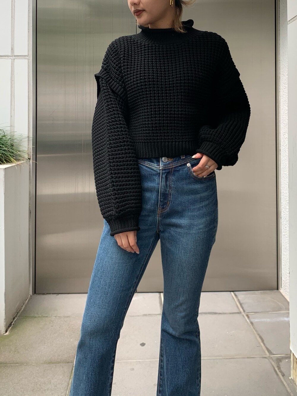 ホワイト系のその他アウター、ブラック系のニット/セーター、ブルー系のデニムパンツを着用したレディースの秋コーディネートの6枚目の写真