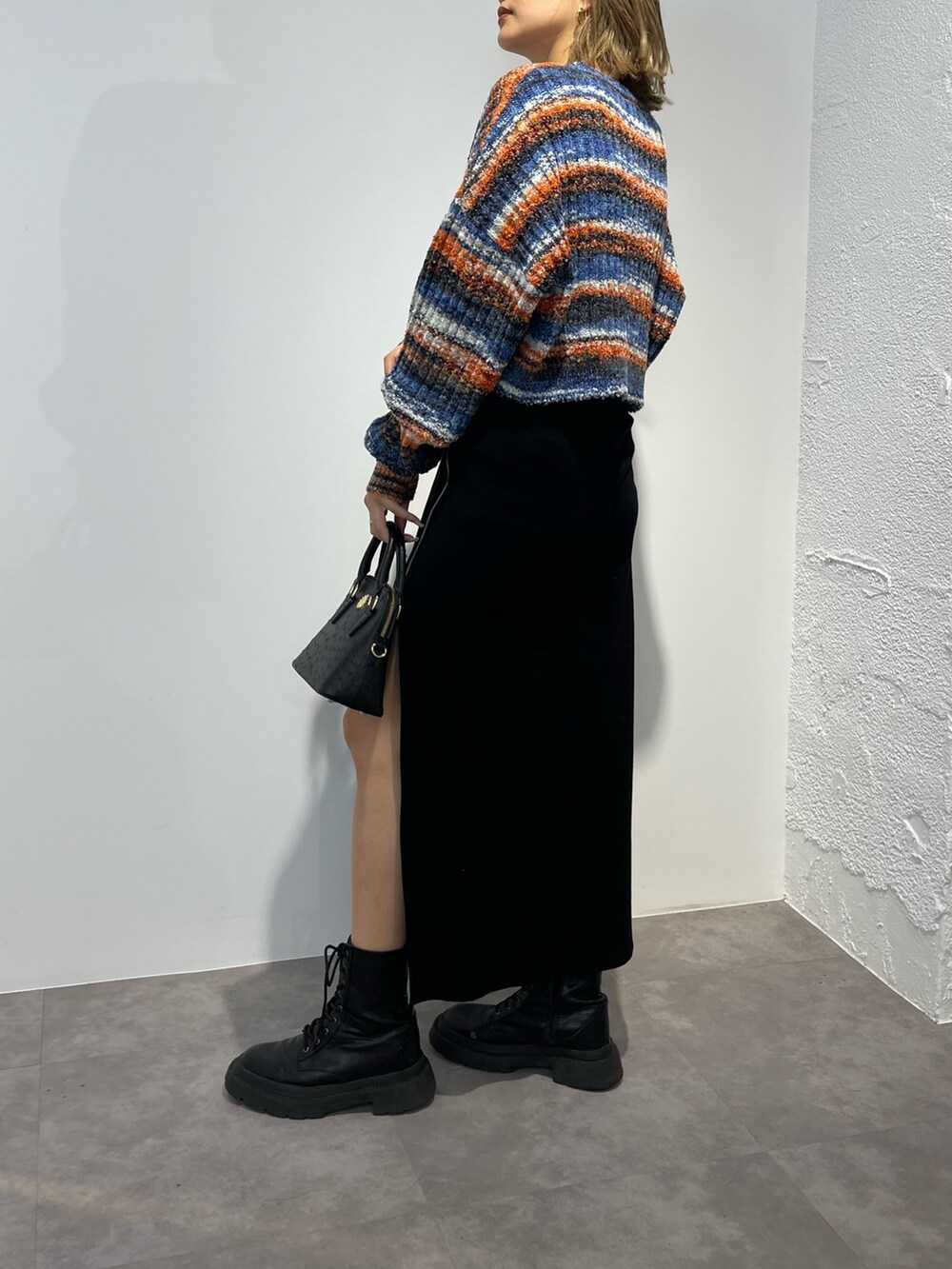 ブラック系のスカート、オレンジ系のニット/セーター、ブラック系のショルダーバッグを着用したレディースの秋コーディネートの5枚目の写真
