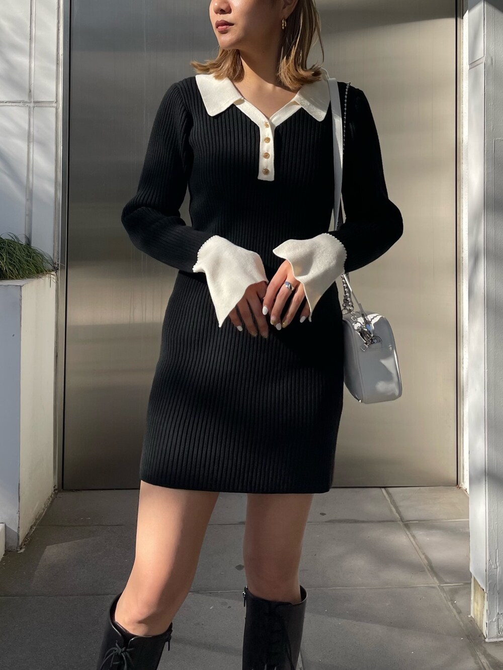 ブラック系のブーツ、ブラック系のワンピース、ホワイト系のショルダーバッグを着用したレディースの冬コーディネートの3枚目の写真