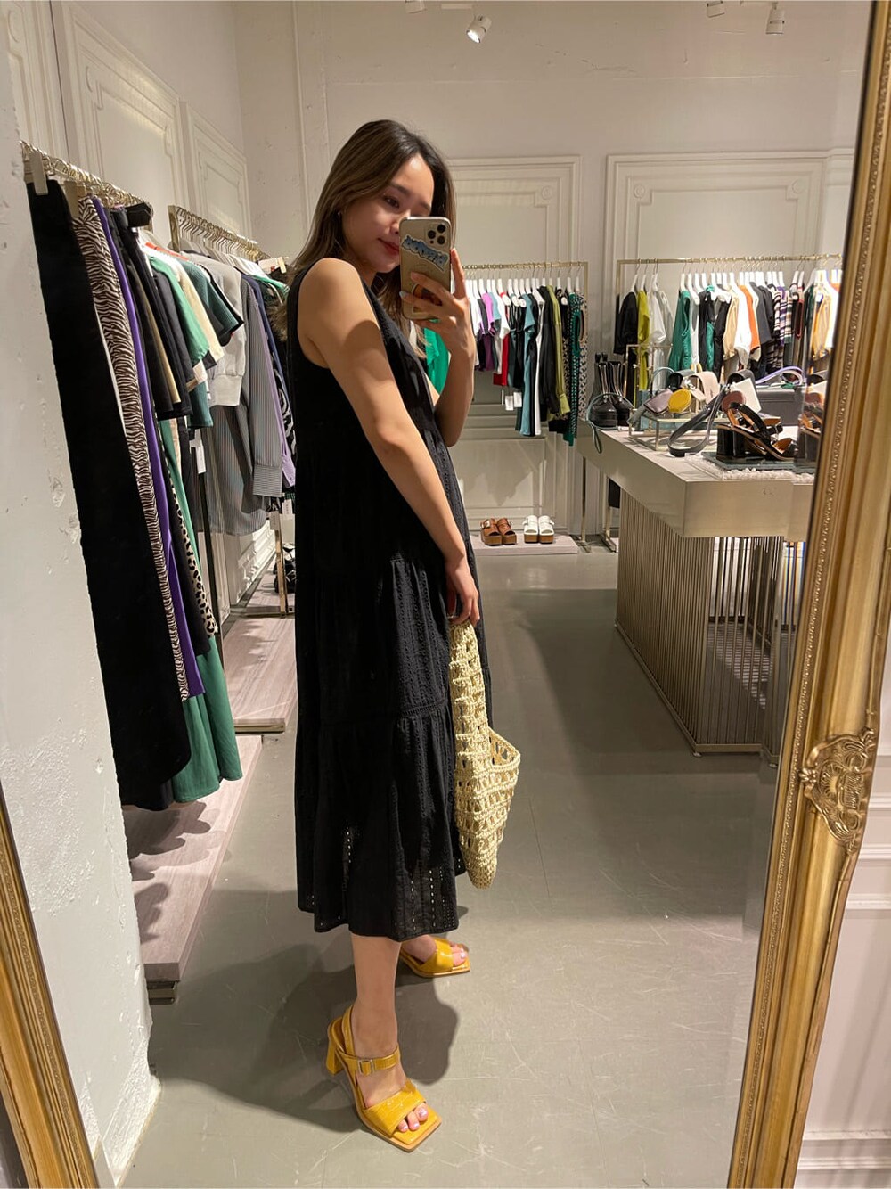 ベージュ系のショルダーバッグ、ブラック系のワンピース、イエロー系のサンダルを着用したレディースの春コーディネートの2枚目の写真