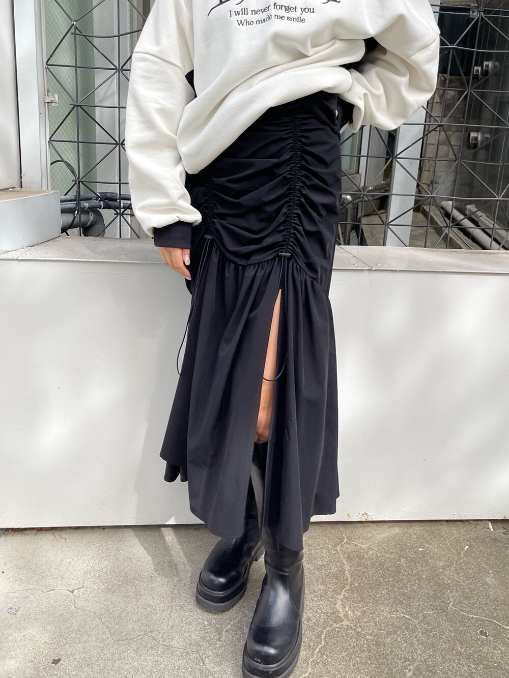 ホワイト系のスウェット、ブラック系のスカート、ブラック系のブーツを着用したレディースの秋コーディネートの6枚目の写真