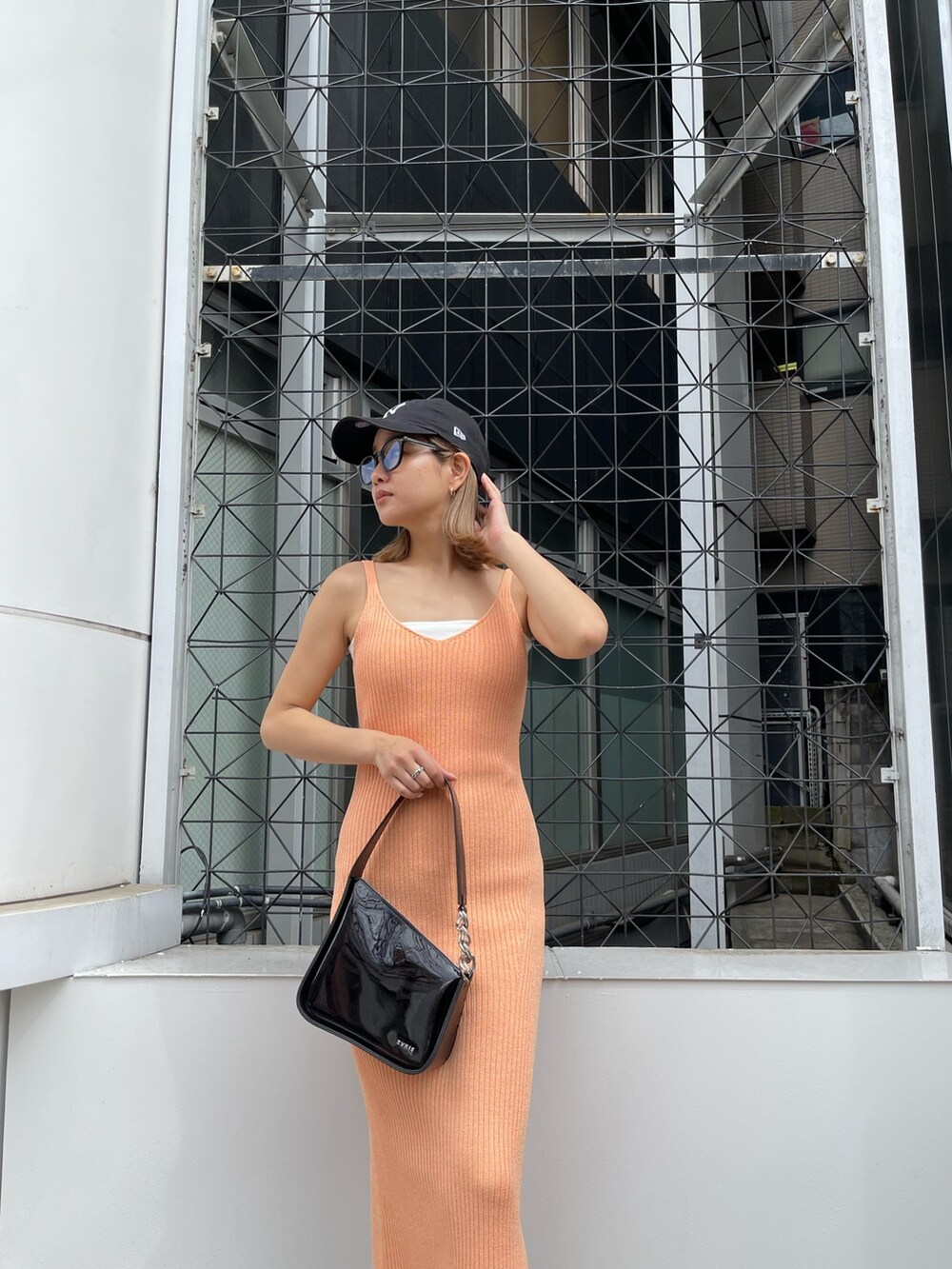 オレンジ系のワンピース、ブラック系のハンドバッグを着用したレディースの春コーディネートの7枚目の写真