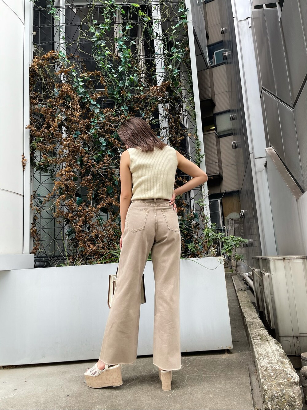 ベージュ系のデニムパンツ、ホワイト系のタンクトップ、ホワイト系のサンダルを着用したレディースの春コーディネートの2枚目の写真