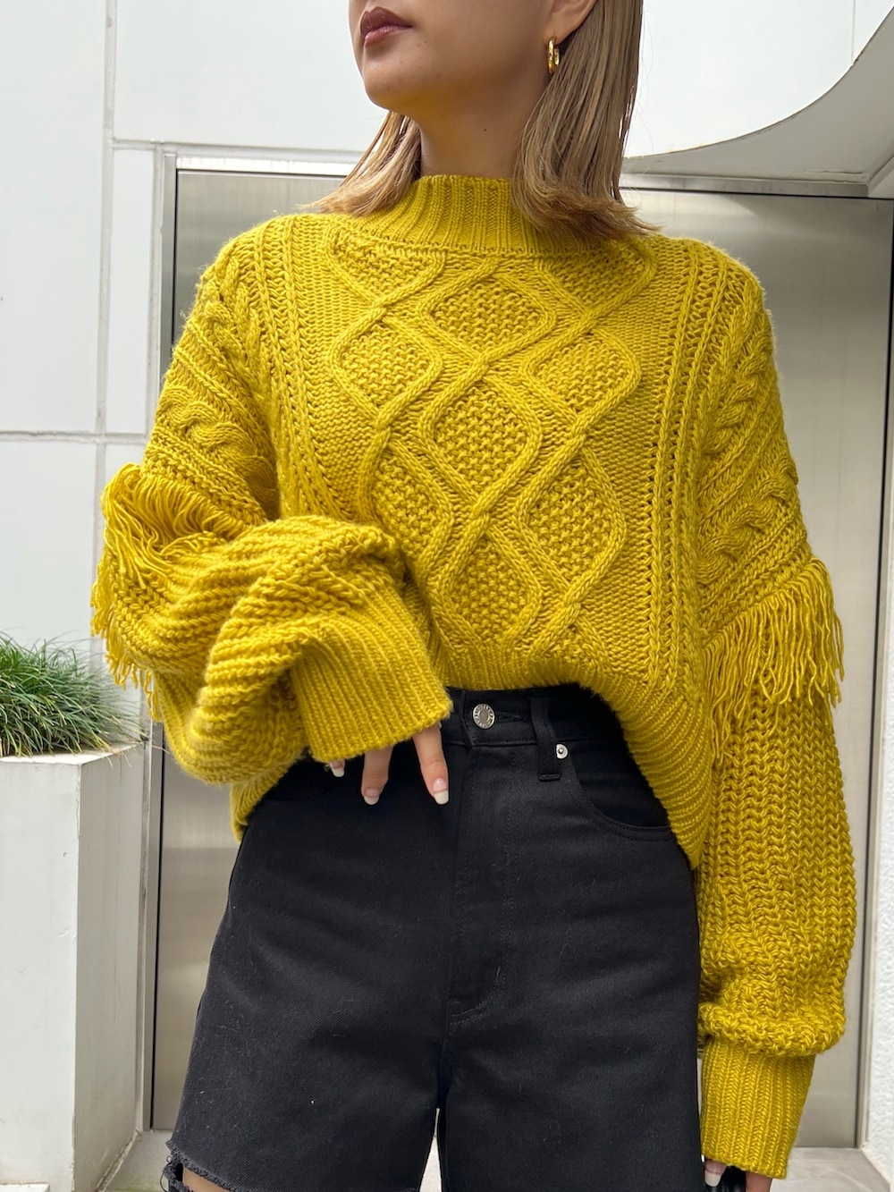 ブラック系のショルダーバッグ、イエロー系のニット/セーター、ブラック系のデニムパンツを着用したレディースの秋コーディネートの4枚目の写真