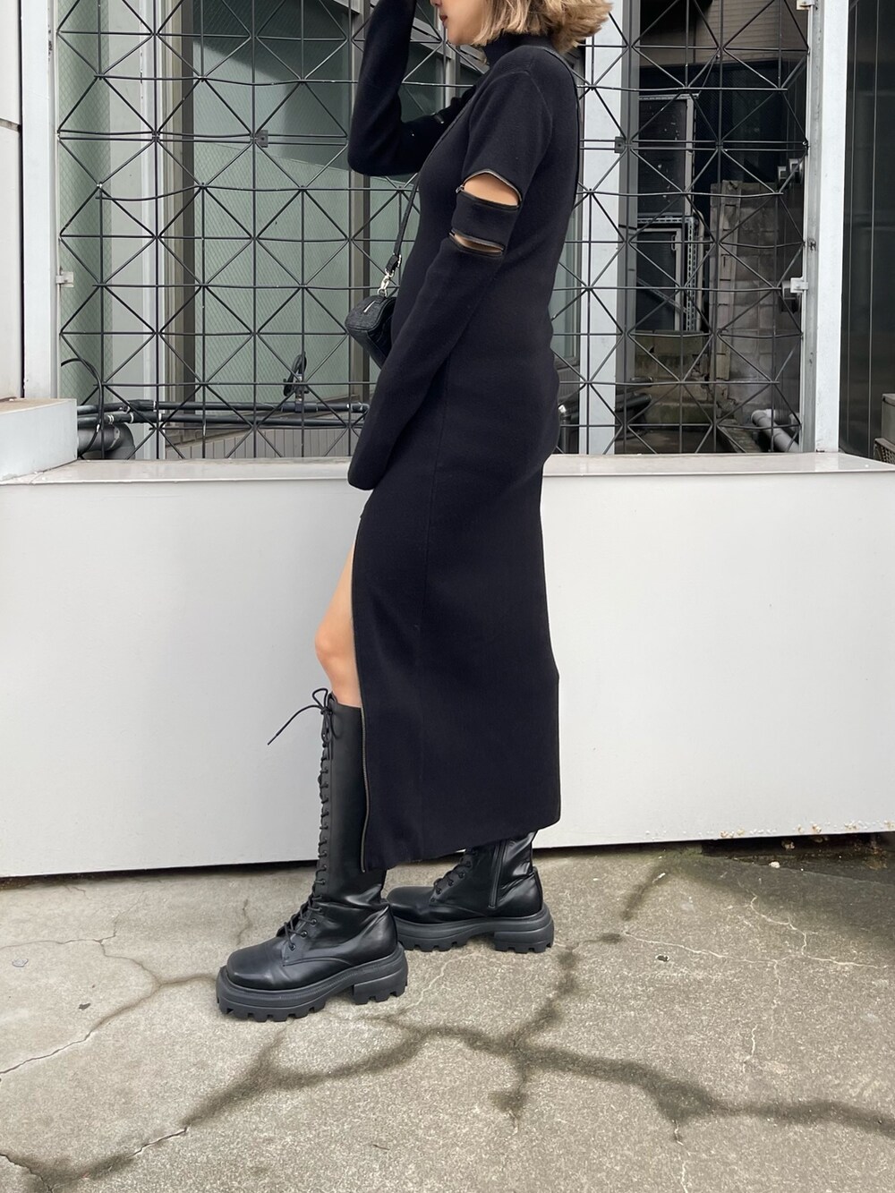 ブラック系のワンピース、ブラック系のハンドバッグ、ブラック系のブーツを着用したレディースの秋コーディネートの2枚目の写真