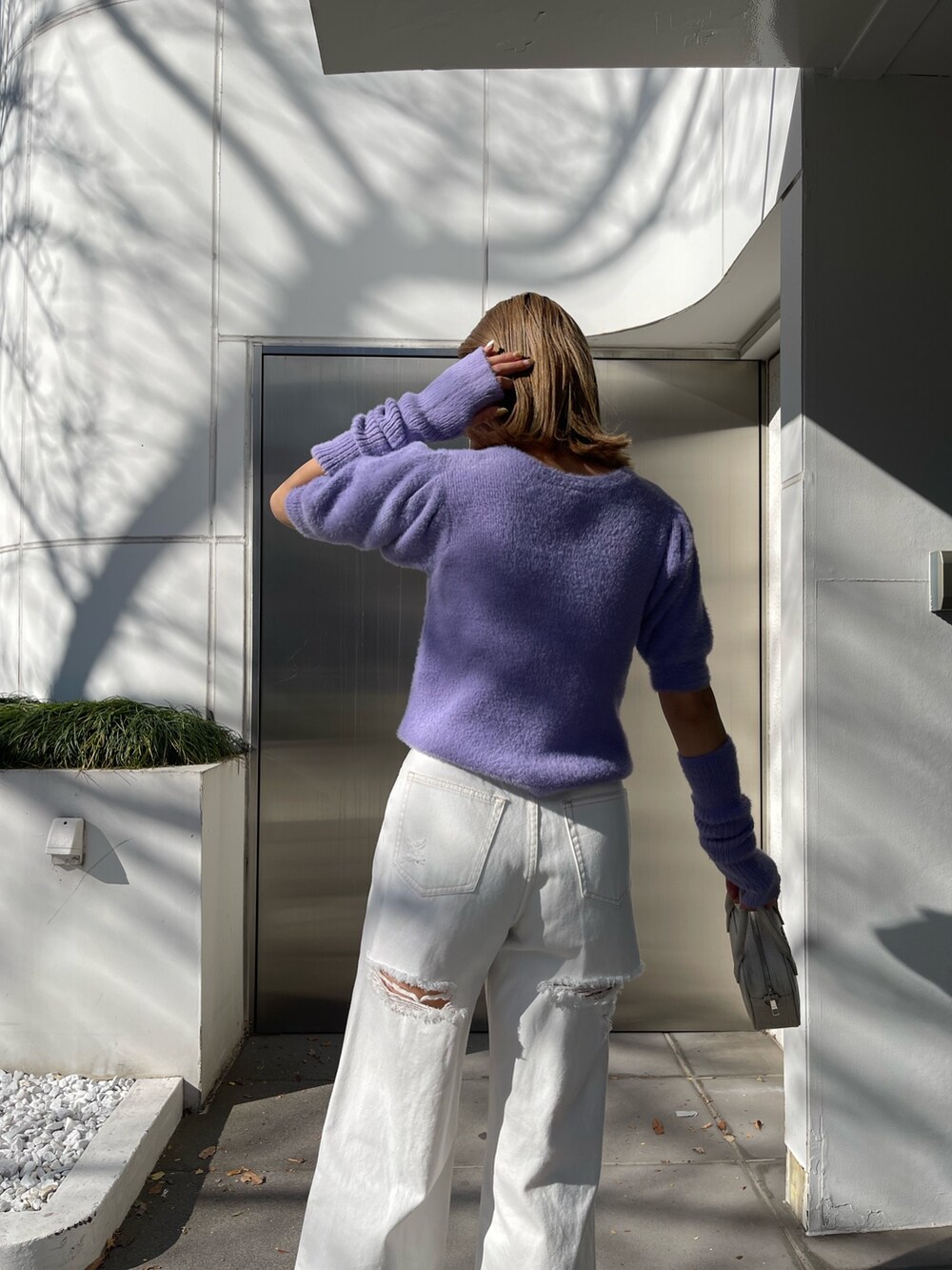 パープル系のニット/セーター、ホワイト系のデニムパンツ、ホワイト系のショルダーバッグを着用したレディースの冬コーディネートの6枚目の写真