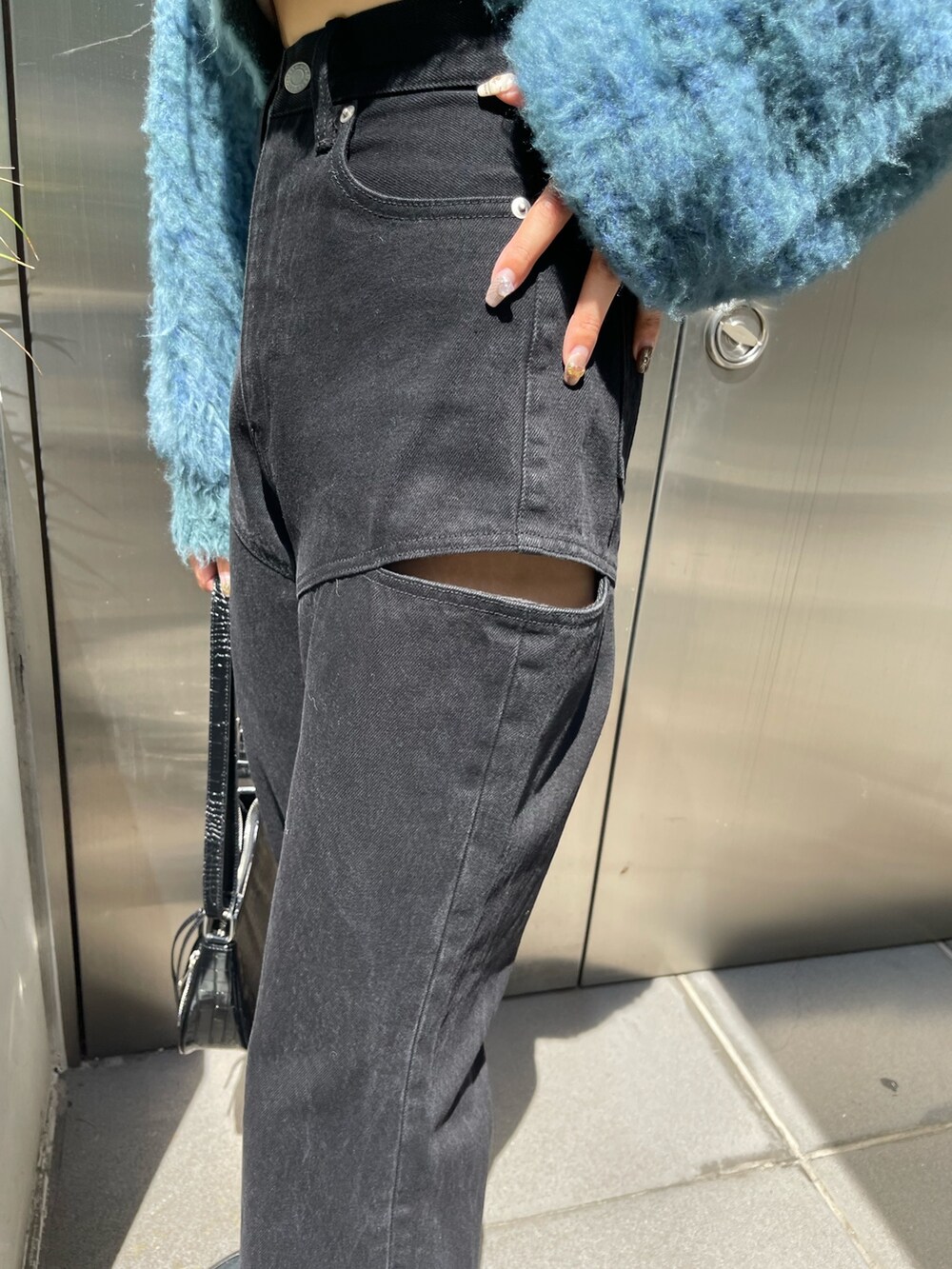 ブラック系のデニムパンツ、ブラウン系のカーディガン/ボレロ、ゴールド系のピアス（両耳用）を着用したレディースの秋コーディネートの7枚目の写真