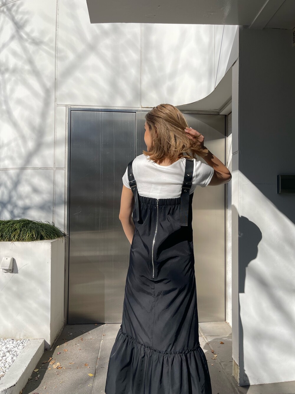 ブラック系のワンピース、ホワイト系のショルダーバッグ、ブラック系のブーツを着用したレディースの冬コーディネートの5枚目の写真