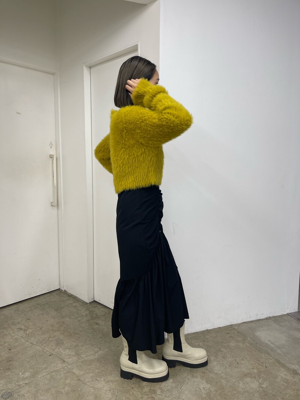 ブラック系のスカート、ホワイト系のブーツ、イエロー系のニット/セーターを着用したレディースの秋コーディネートの6枚目の写真