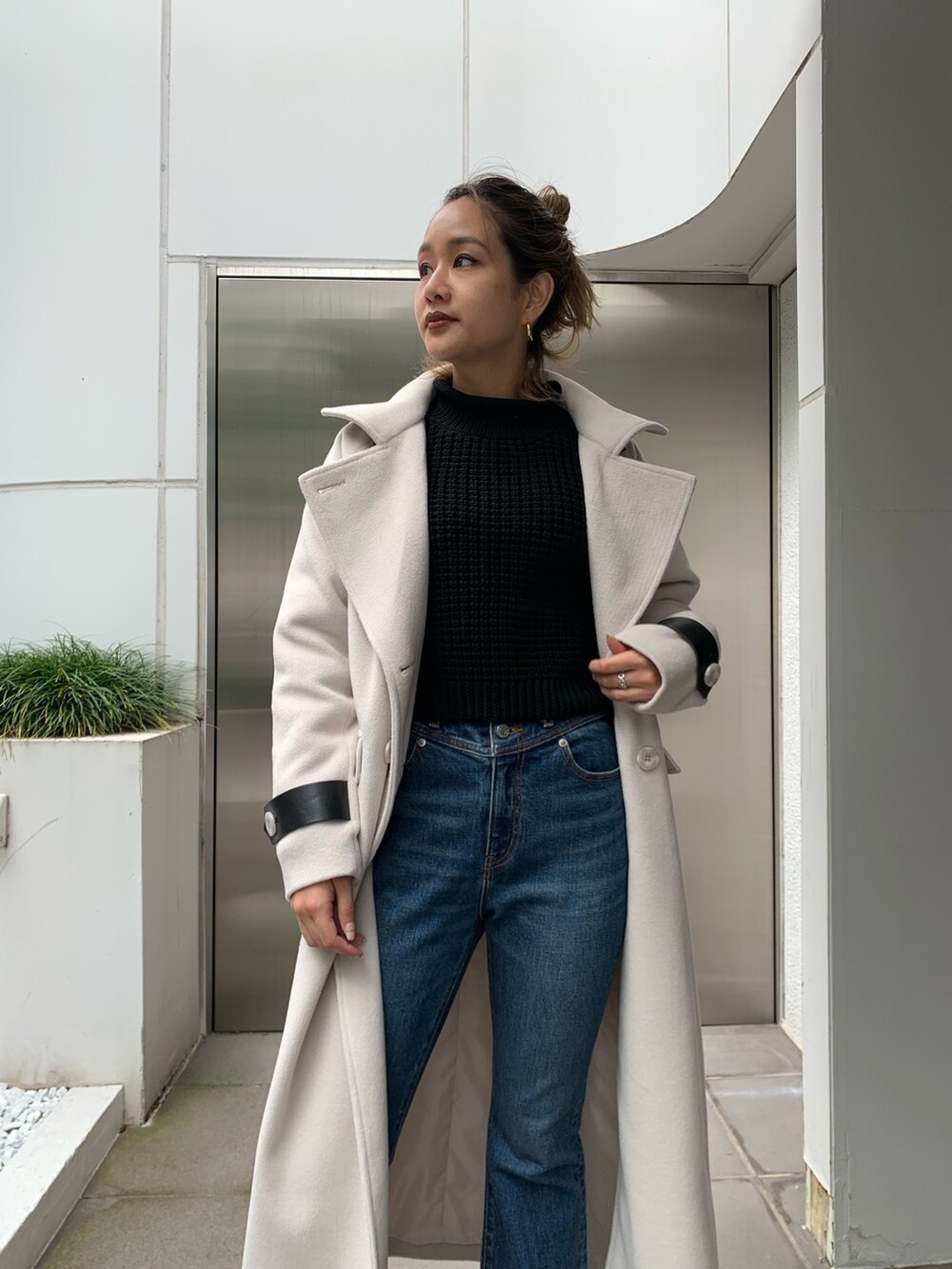 ホワイト系のその他アウター、ブラック系のニット/セーター、ブルー系のデニムパンツを着用したレディースの秋コーディネートの4枚目の写真