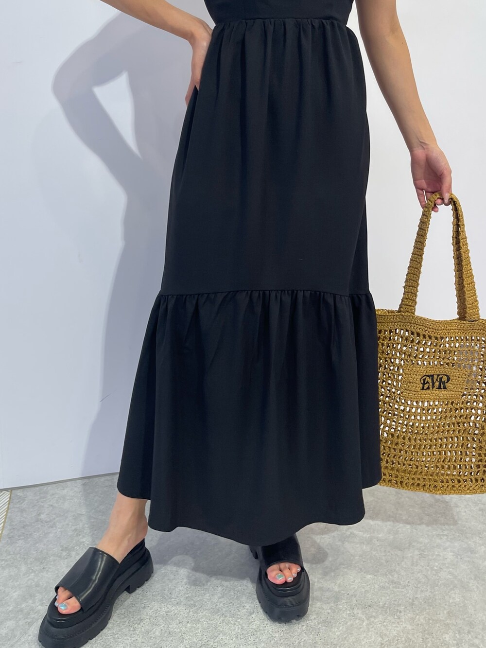 ベージュ系のトートバッグ、ブラック系のワンピース、ブラック系のサンダルを着用したレディースの夏コーディネートの6枚目の写真