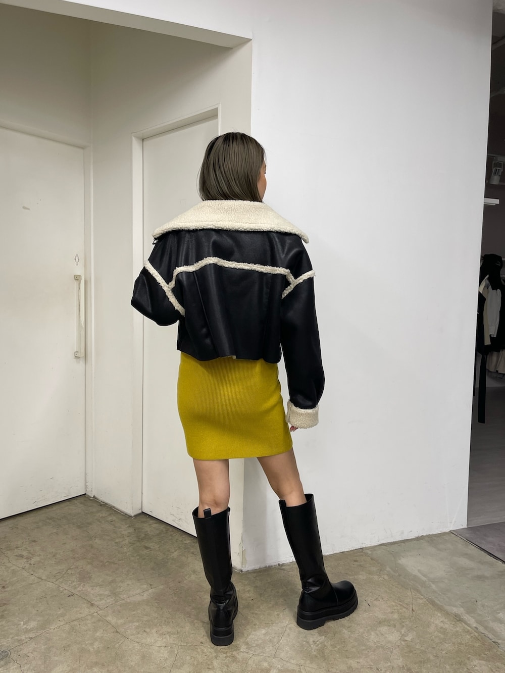 イエロー系のワンピース、ブラック系のブーツ、ブラック系のムートンコートを着用したレディースの秋コーディネートの4枚目の写真