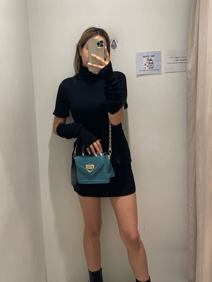 ブラック系のブーツ、ブラック系のワンピース、グリーン系のショルダーバッグを着用したレディースの秋コーディネートの3枚目の写真