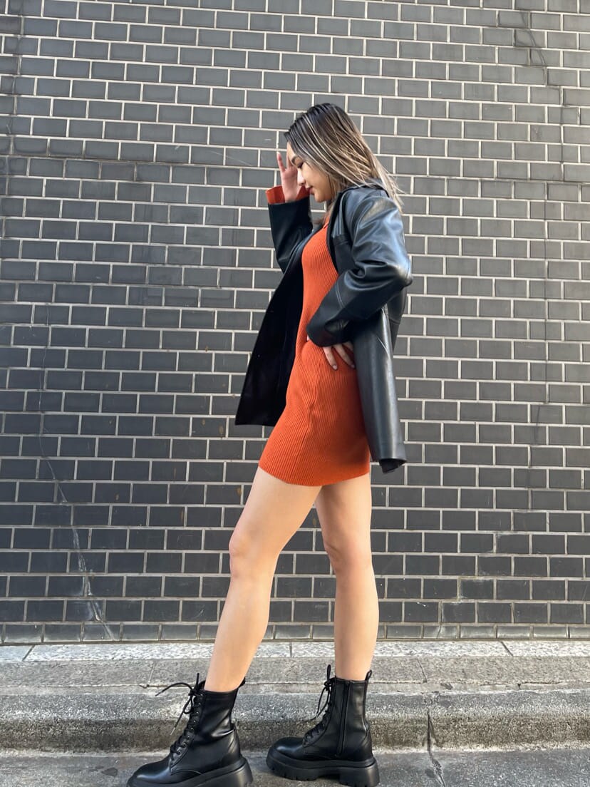 オレンジ系のワンピース、ブラック系のテーラードジャケット、ブラック系のブーツを着用したレディースの冬コーディネートの3枚目の写真