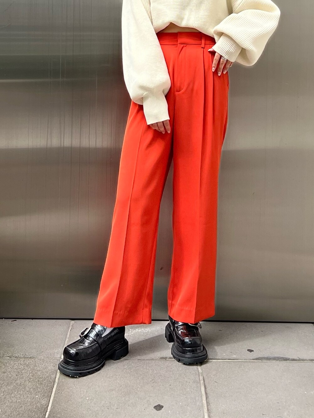 オレンジ系のスラックス、ホワイト系のニット/セーター、ブラック系のローファーを着用したレディースの秋コーディネートの6枚目の写真