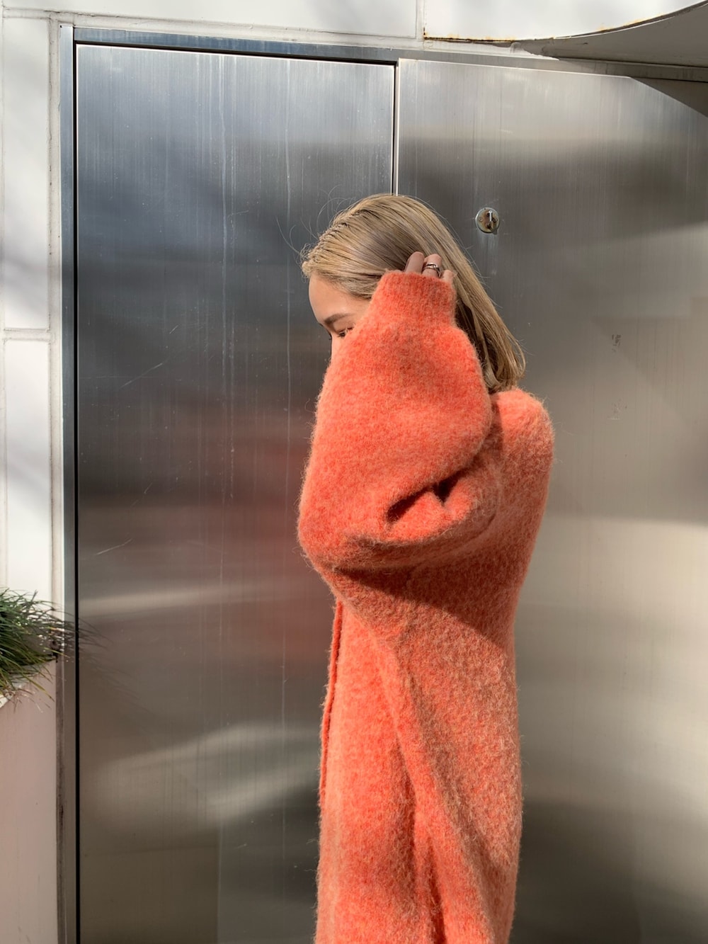 ブラック系のハンドバッグ、オレンジ系のカーディガン/ボレロ、ホワイト系のTシャツ/カットソーを着用したレディースの冬コーディネートの5枚目の写真