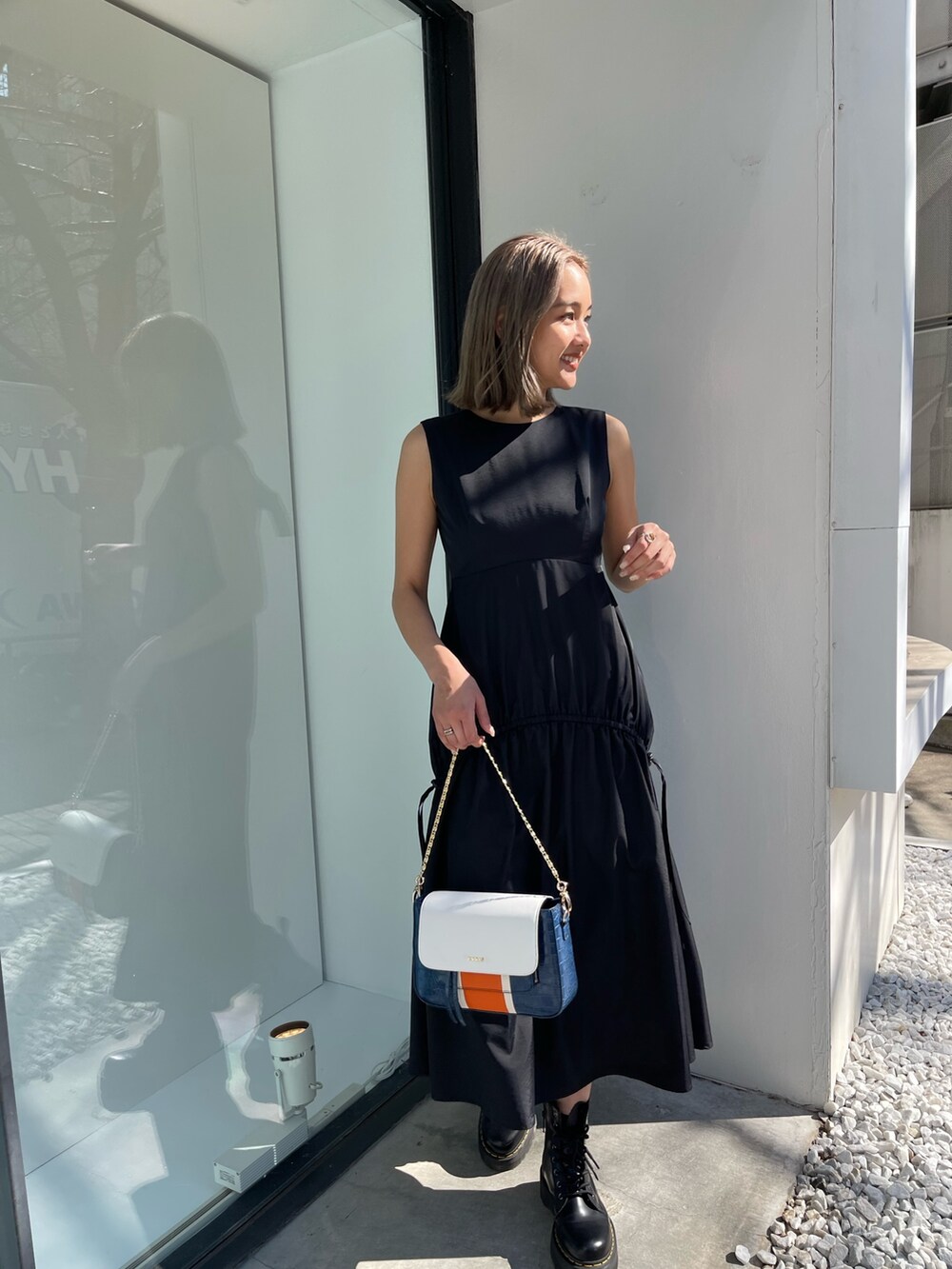 ブラック系のブーツ、ブルー系のショルダーバッグ、ブラック系のワンピースを着用したレディースの春コーディネートの7枚目の写真