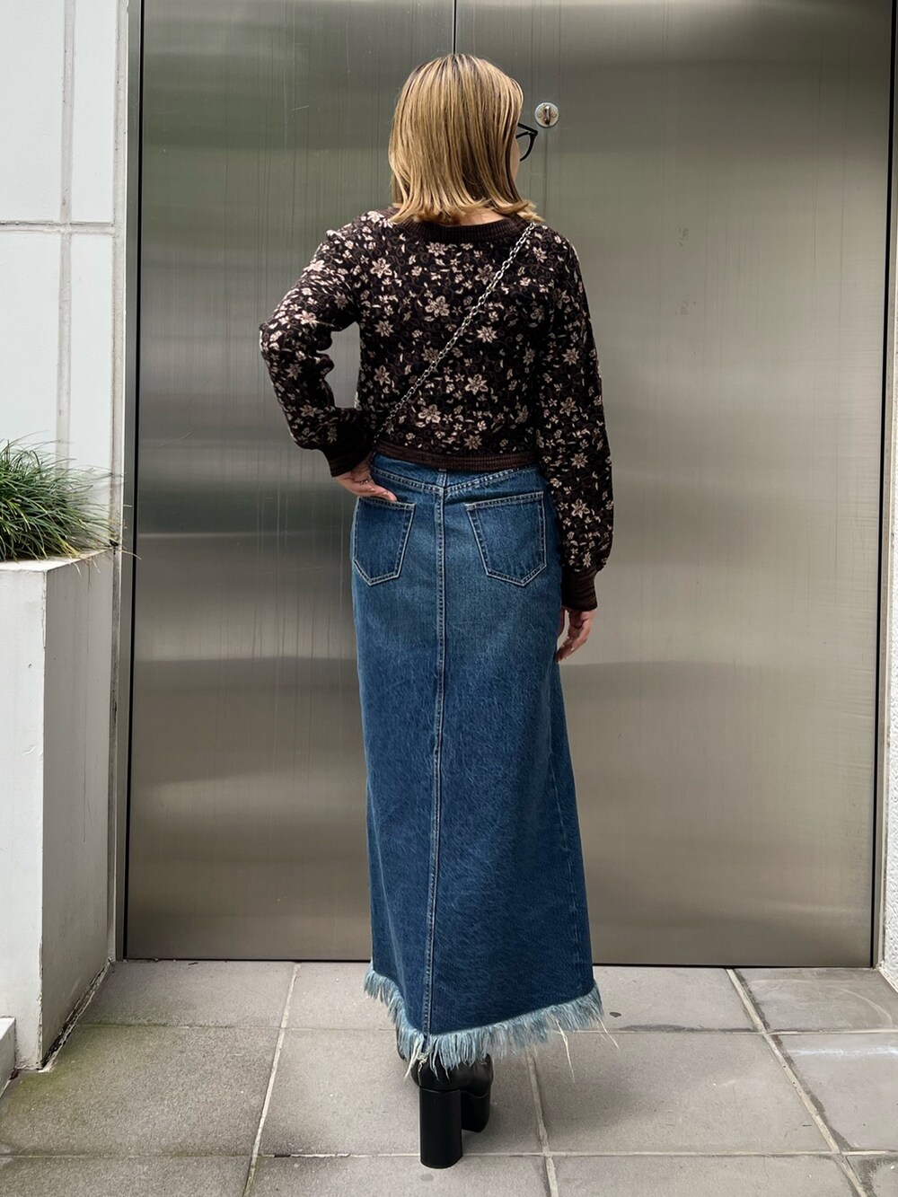 ブルー系のデニムスカート、ブラック系のブーツ、ブラック系のニット/セーターを着用したレディースの秋コーディネートの3枚目の写真