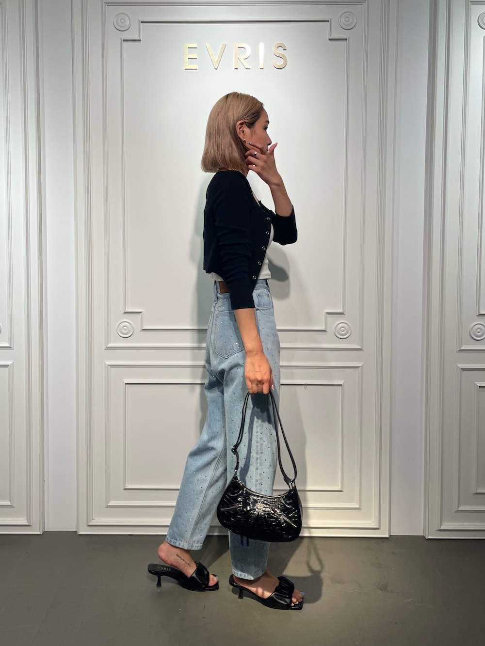 ブラック系のショルダーバッグ、ブルー系のデニムパンツ、ブラック系のサンダルを着用したレディースの夏コーディネートの4枚目の写真