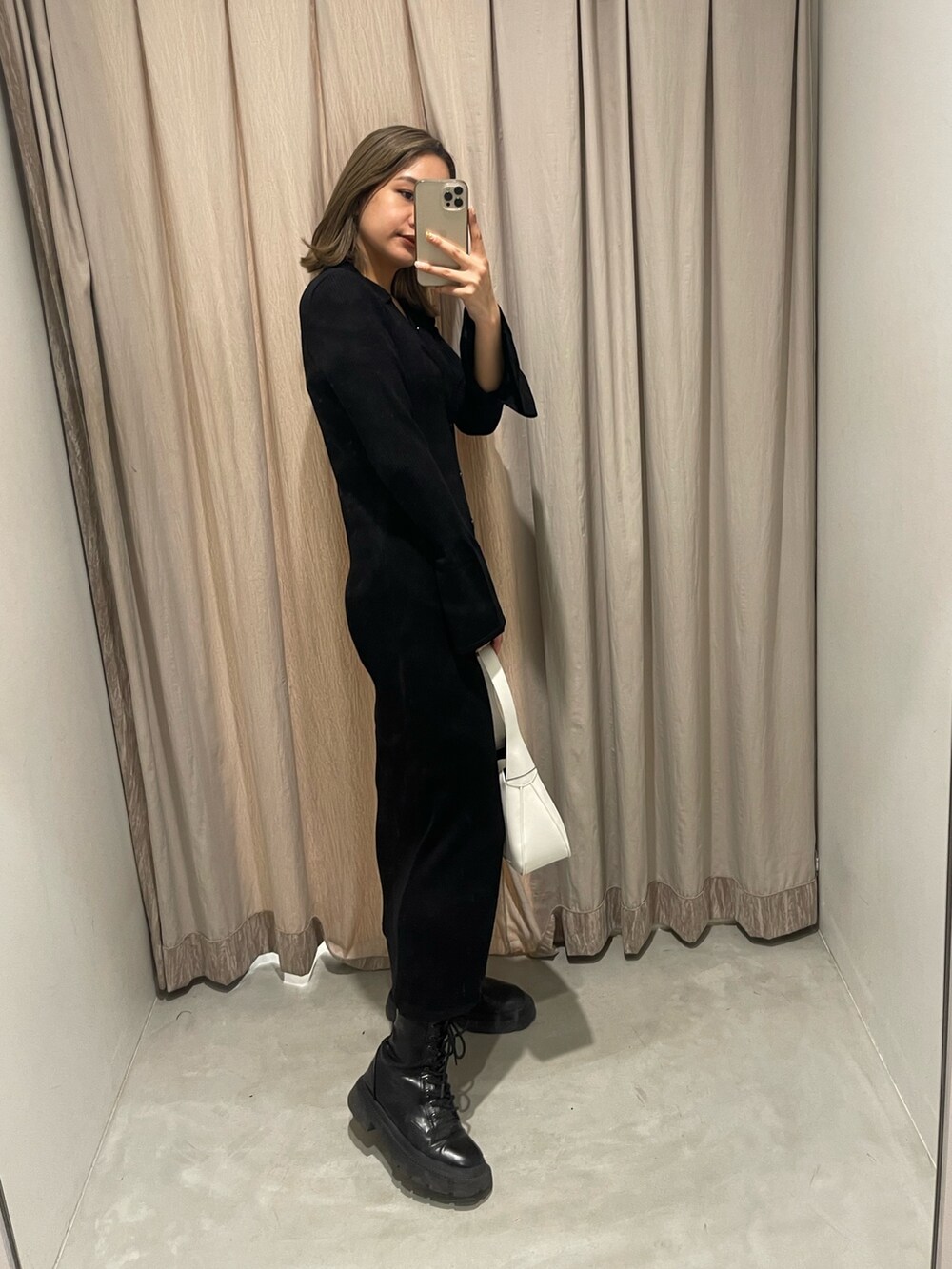 ホワイト系のブーツ、ブラック系のハンドバッグ、ブラック系のワンピースを着用したレディースの冬コーディネートの4枚目の写真