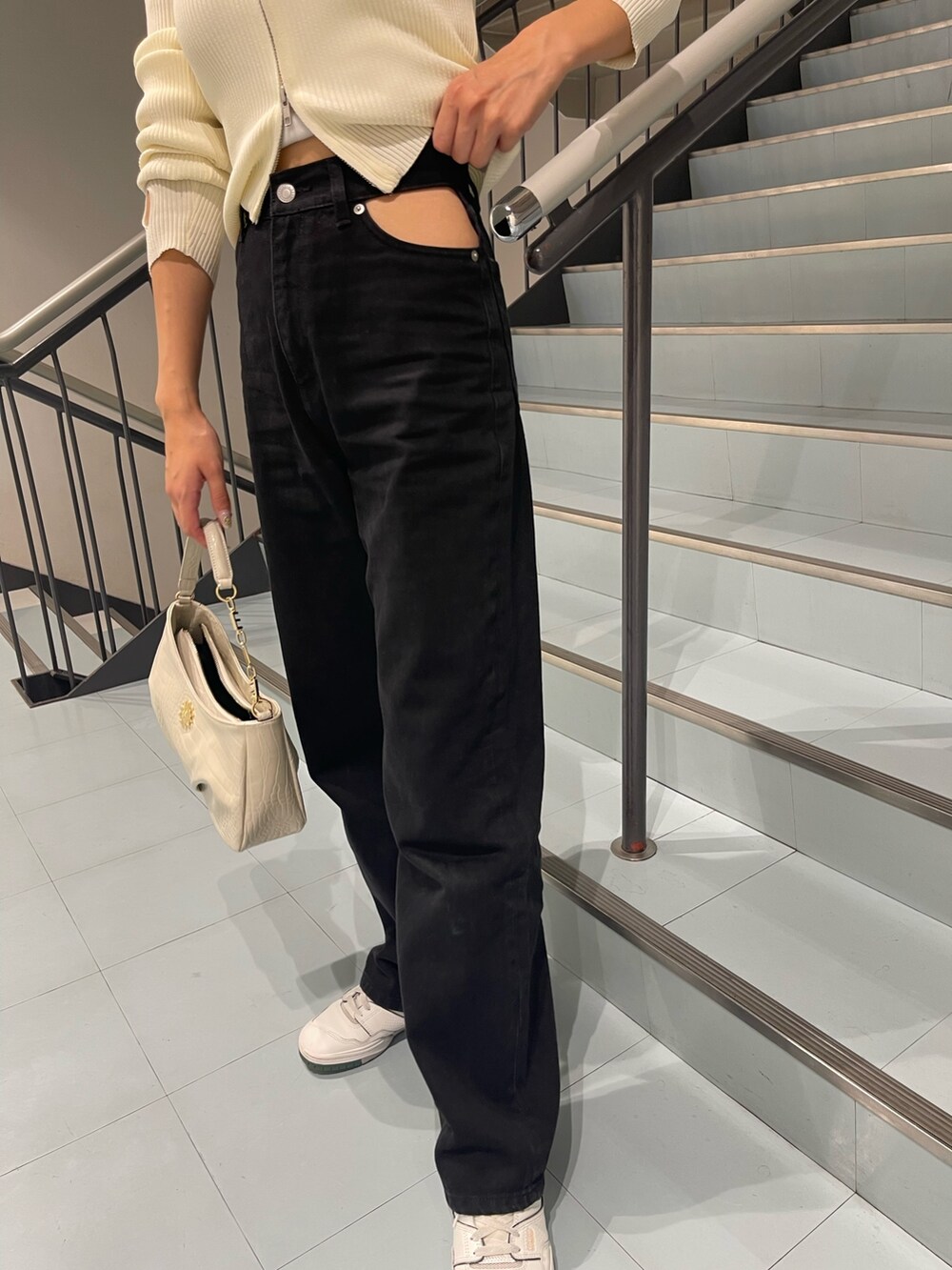 ホワイト系のニット/セーター、ブラック系のデニムパンツ、ホワイト系のハンドバッグを着用したレディースの夏コーディネートの7枚目の写真