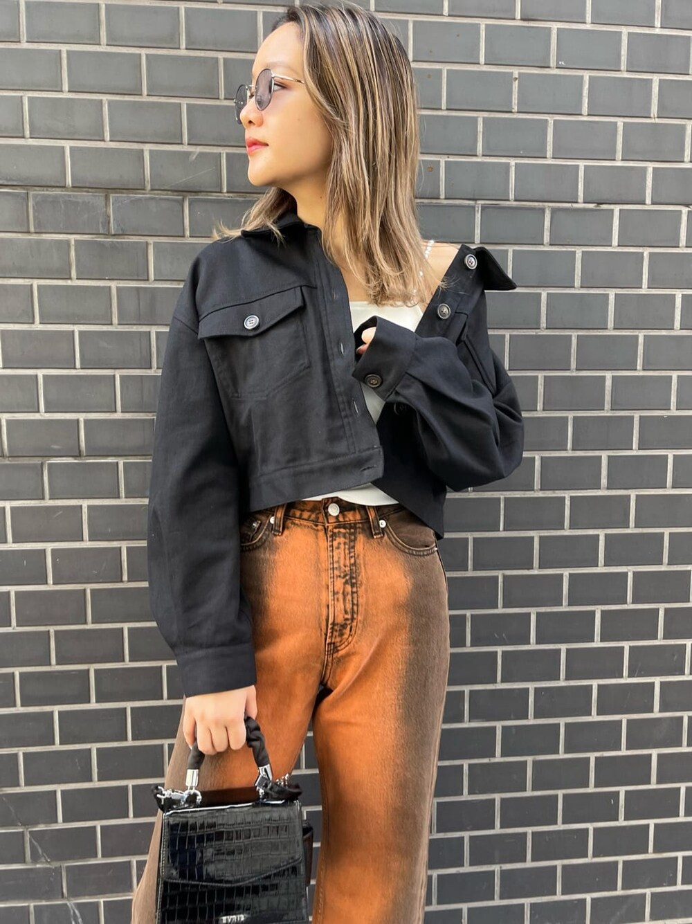 ブラック系のブルゾン、ブラック系のブーツ、ホワイト系のキャミソールを着用したレディースの春コーディネートの5枚目の写真