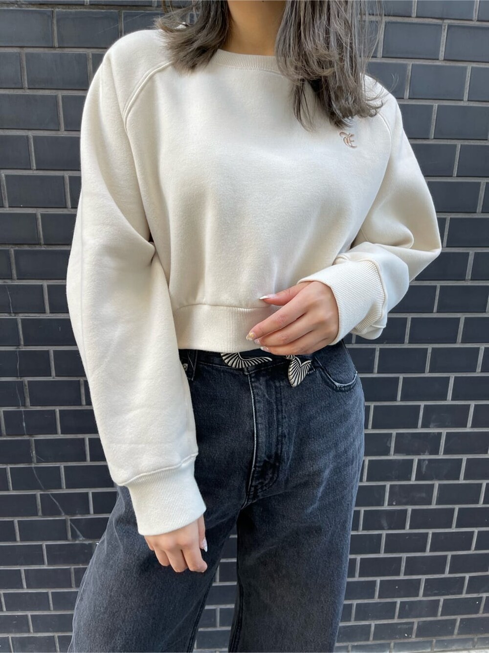 ブラック系のデニムパンツ、ブラック系のブーツ、ホワイト系のスウェットを着用したレディースの冬コーディネートの6枚目の写真