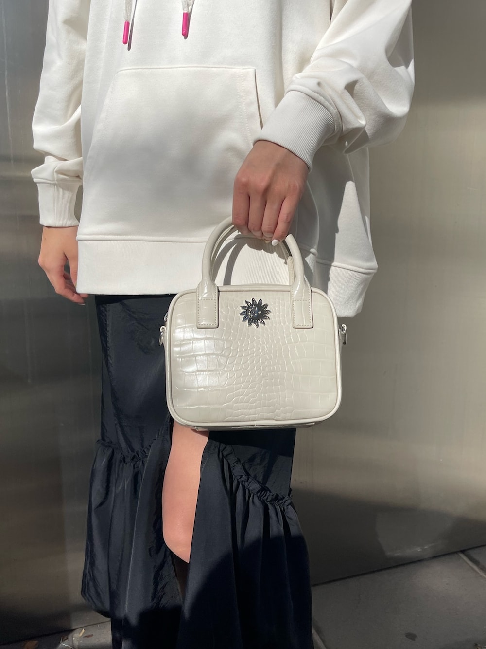 ホワイト系のパーカー、ホワイト系のショルダーバッグ、ブラック系のブーツを着用したレディースの冬コーディネートの7枚目の写真