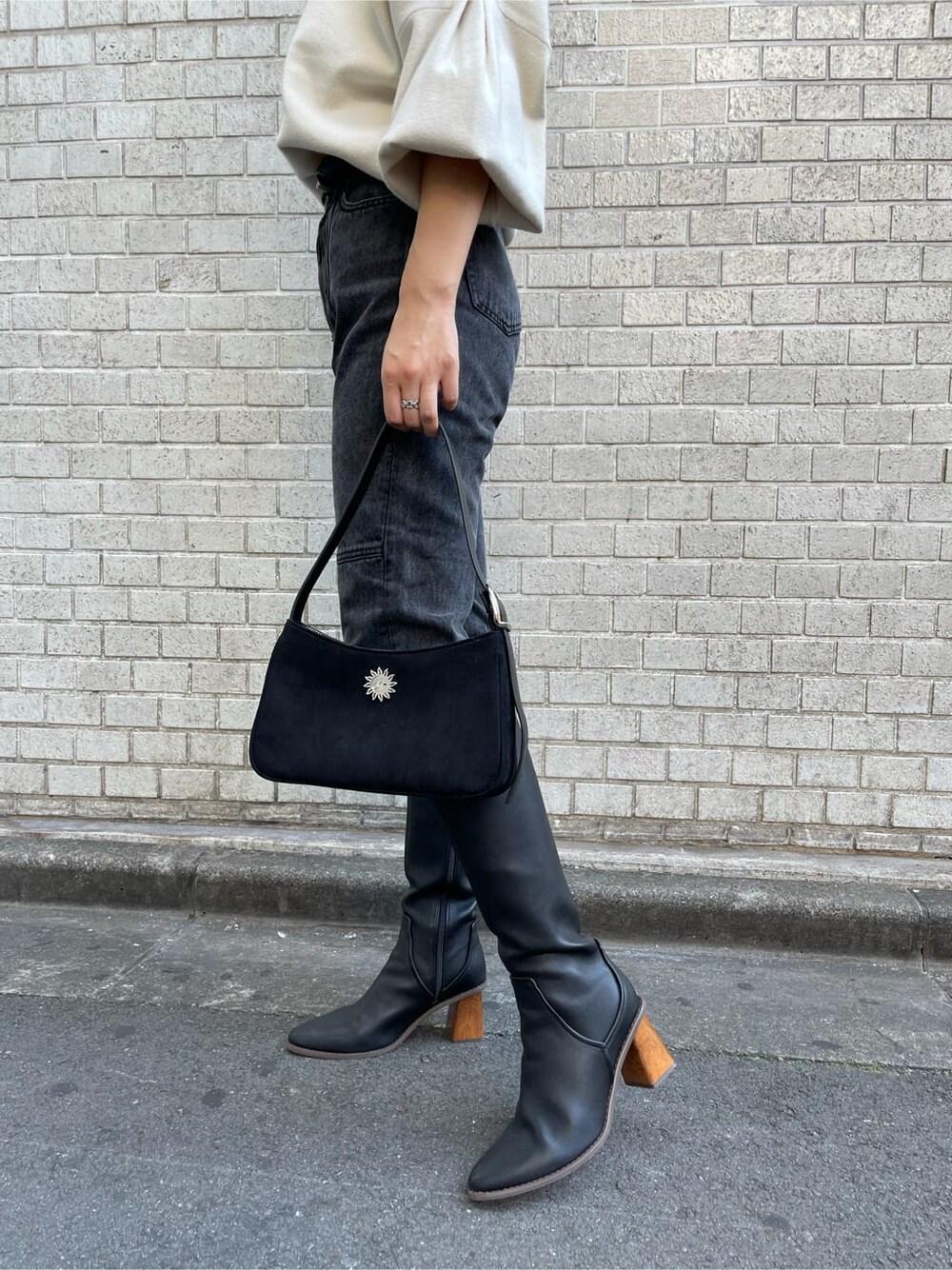 ブラック系のショルダーバッグ、ブラック系のデニムパンツ、ホワイト系のニット/セーターを着用したレディースの秋コーディネートの8枚目の写真