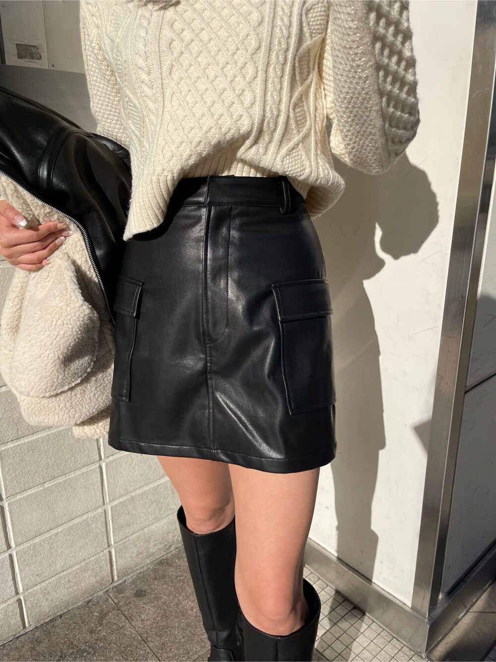 ブラック系のブルゾン、ブラック系のブーツ、ホワイト系のニット/セーターを着用したレディースの冬コーディネートの5枚目の写真