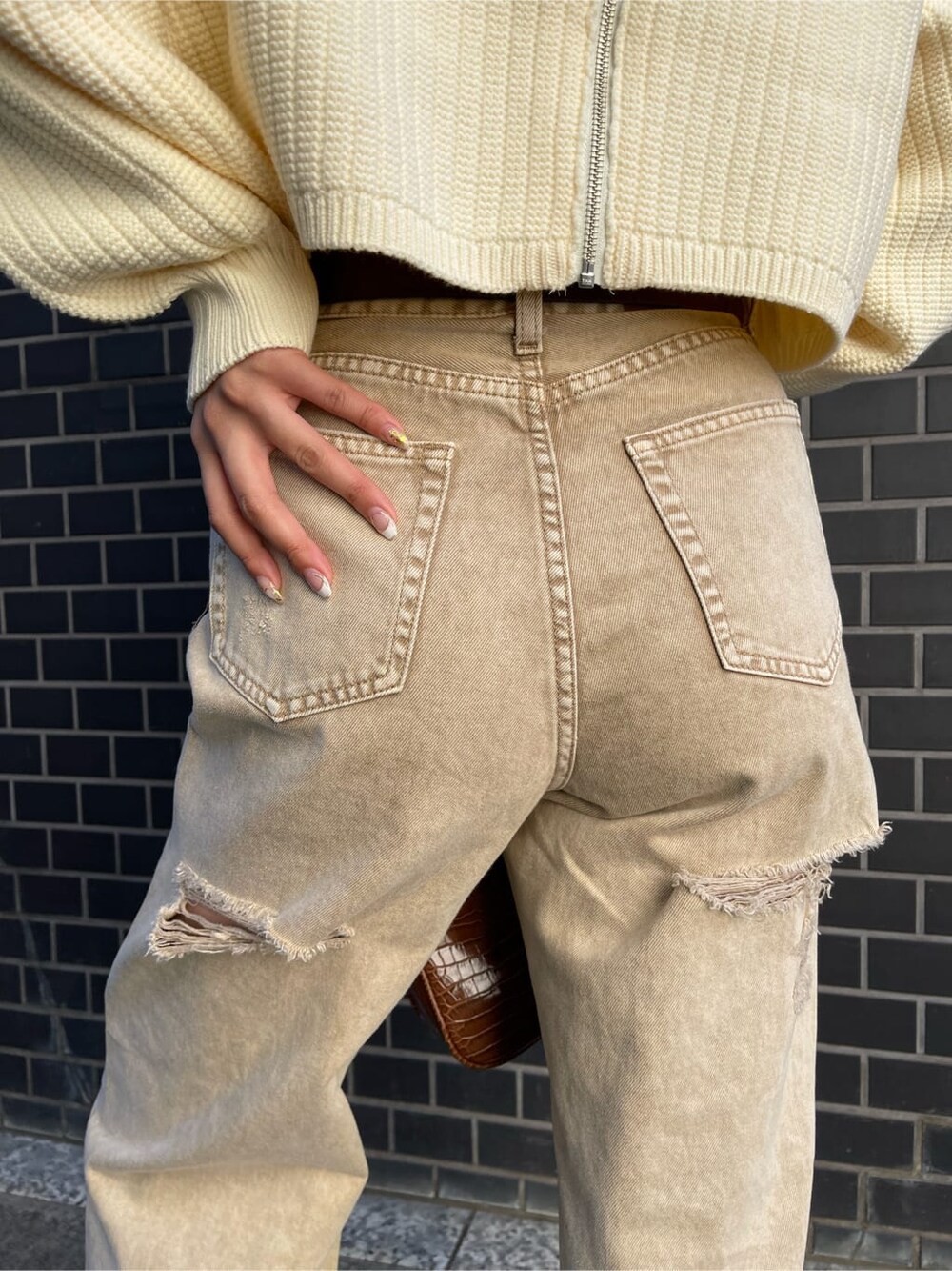 ベージュ系のデニムパンツ、ブラウン系のショルダーバッグ、ホワイト系のニット/セーターを着用したレディースの冬コーディネートの5枚目の写真