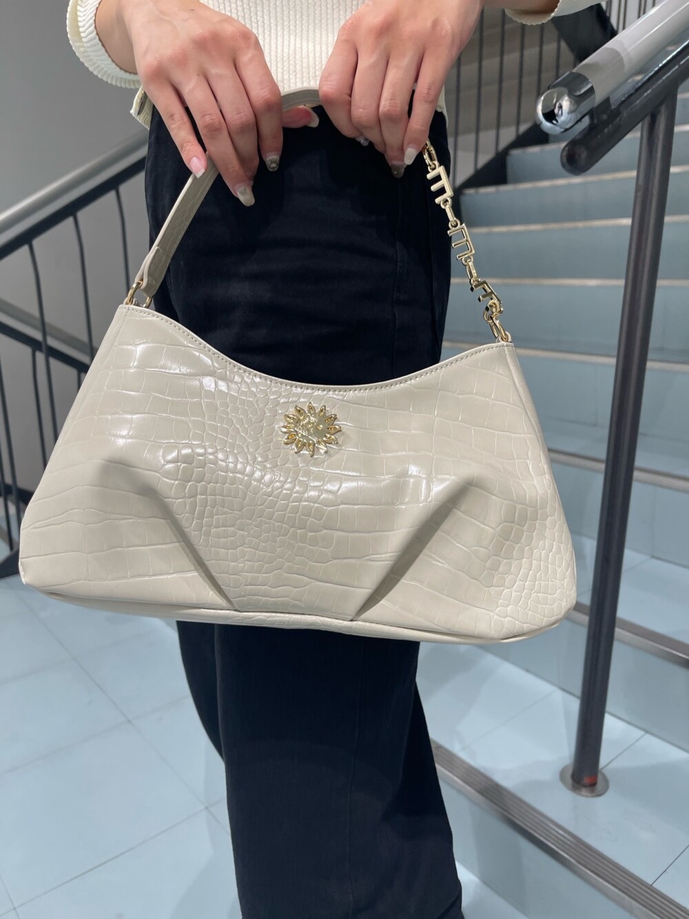 ホワイト系のニット/セーター、ブラック系のデニムパンツ、ホワイト系のハンドバッグを着用したレディースの夏コーディネートの9枚目の写真