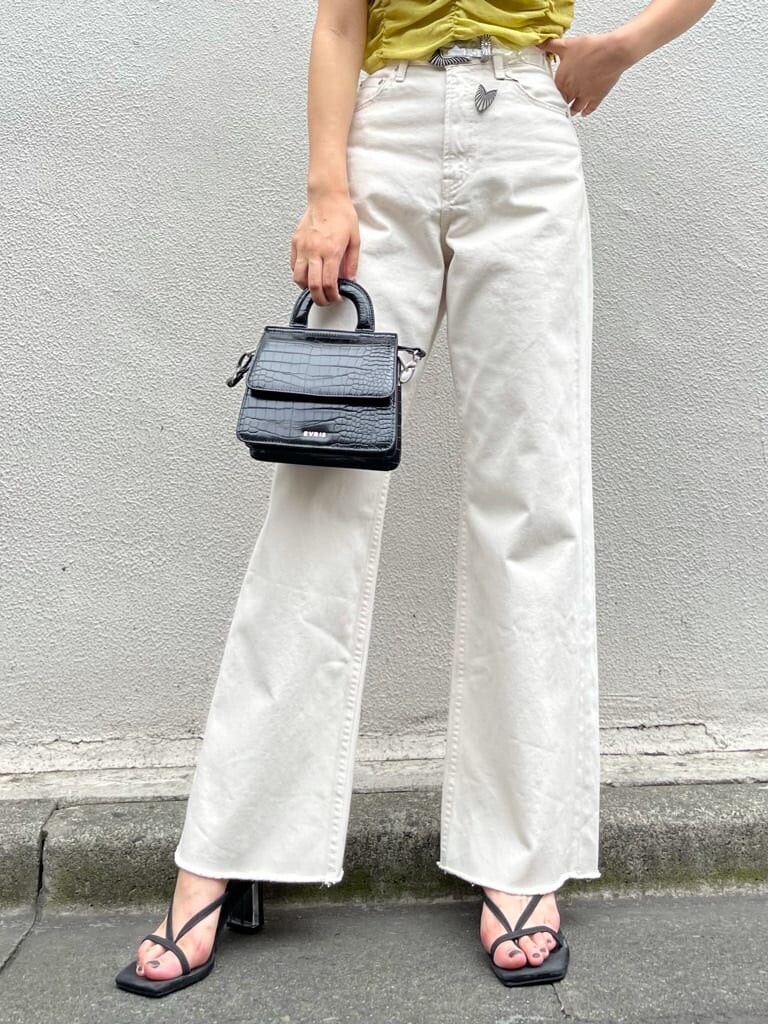 イエロー系のキャミソール、ホワイト系のデニムパンツ、ブラック系のサンダルを着用したレディースの夏コーディネートの5枚目の写真