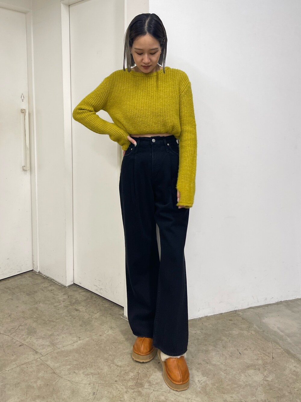 イエロー系のニット/セーター、ブラック系のデニムパンツ、ベージュ系のスリッポンを着用したレディースの秋コーディネートの2枚目の写真