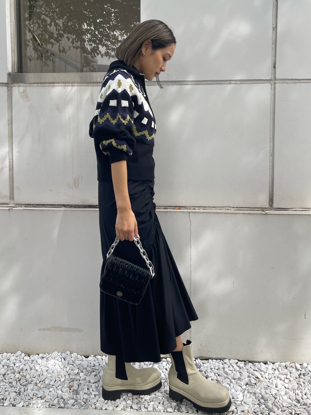 ブラック系のスカート、ホワイト系のブーツ、ブラック系のニット/セーターを着用したレディースの秋コーディネートの3枚目の写真