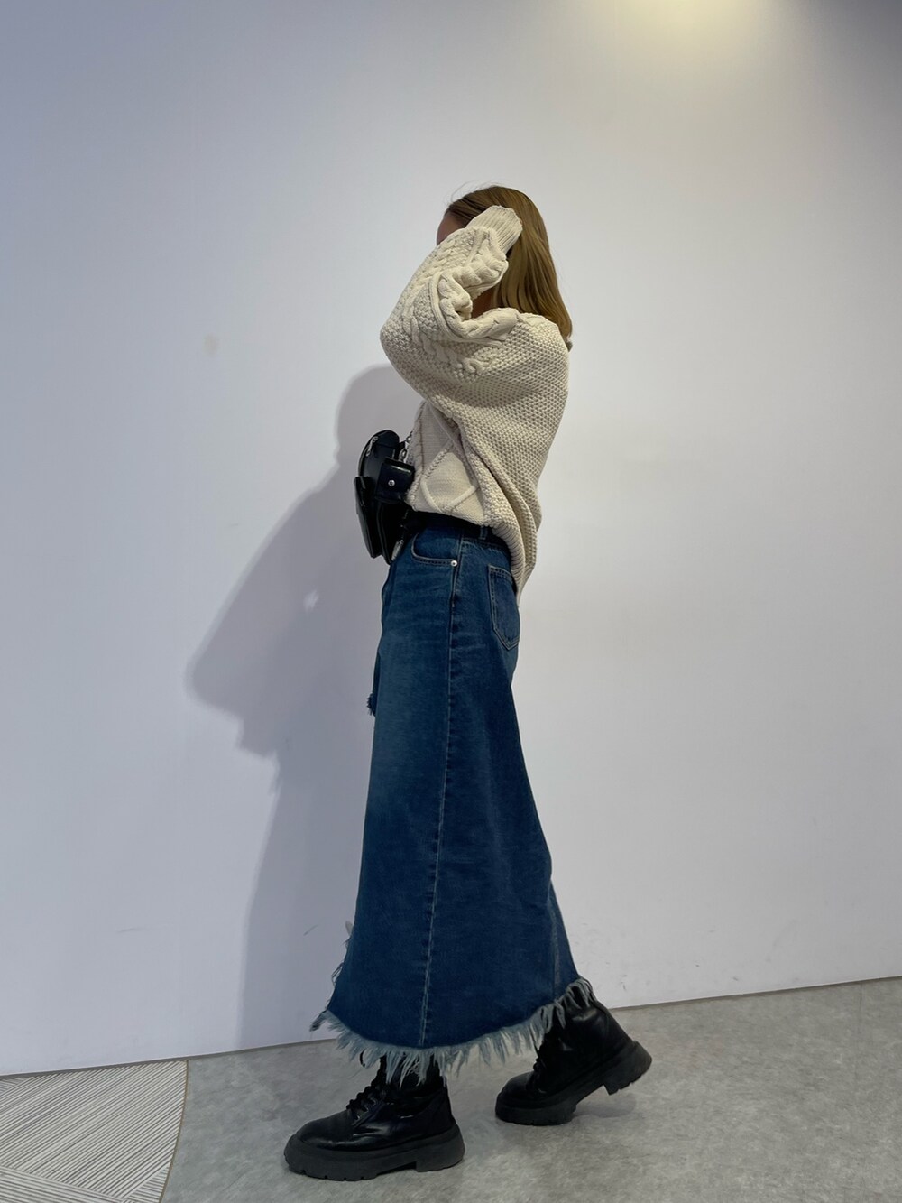 ブルー系のデニムスカート、ブラック系のブーツ、ホワイト系のニット/セーターを着用したレディースの冬コーディネートの3枚目の写真