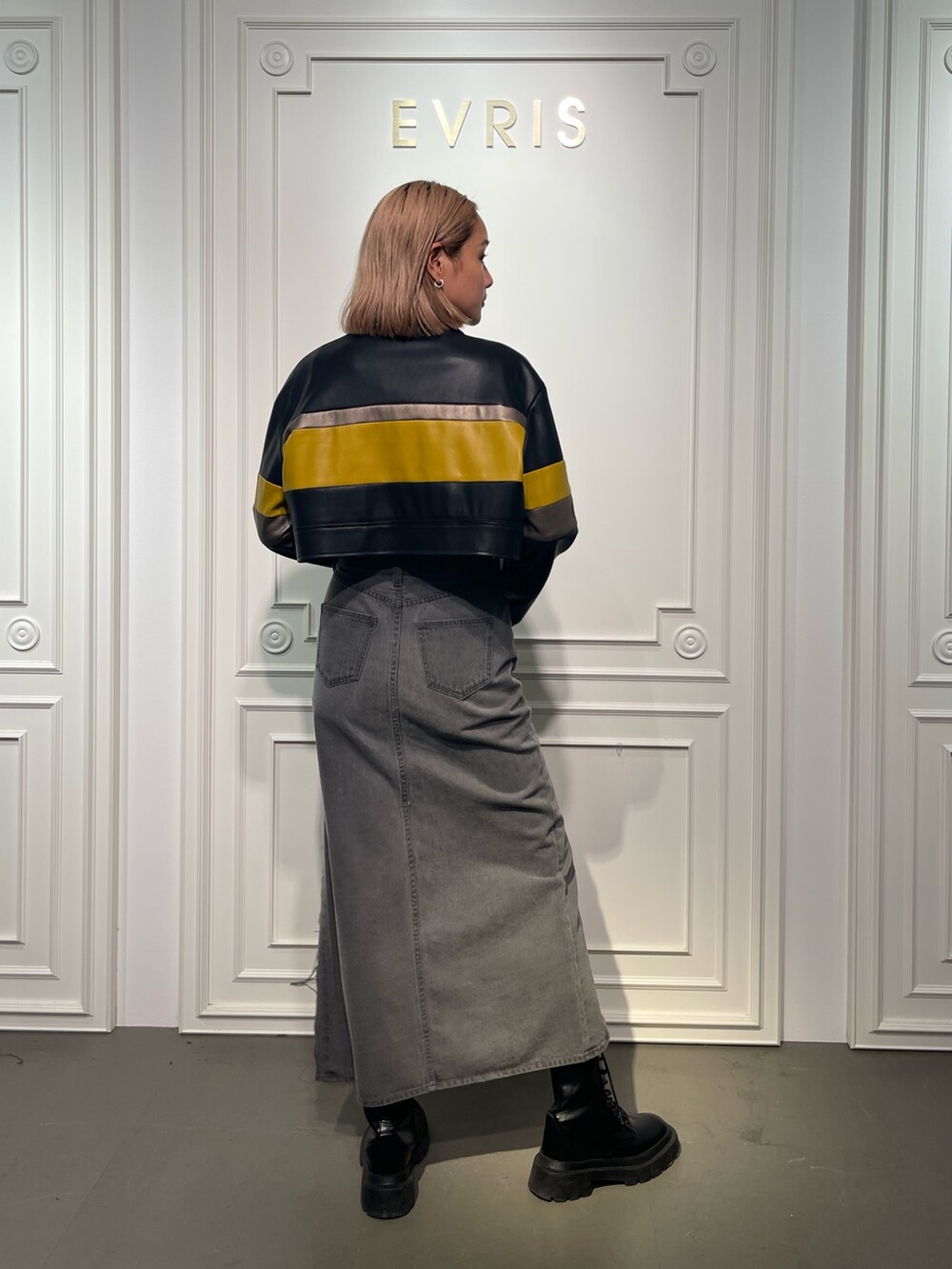 ブラック系のデニムスカート、ブラック系のブーツ、ホワイト系のTシャツ/カットソーを着用したレディースの夏コーディネートの4枚目の写真