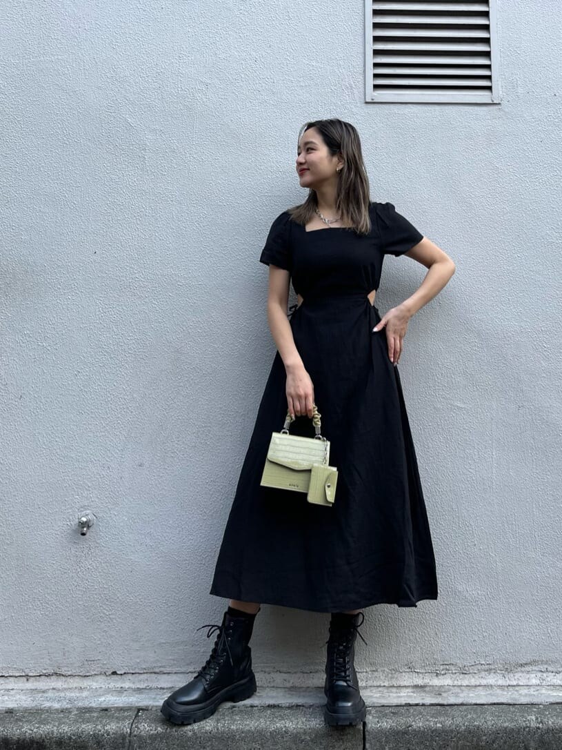 ブラック系のブーツ、グリーン系のショルダーバッグ、ブラック系のワンピースを着用したレディースの春コーディネートの2枚目の写真