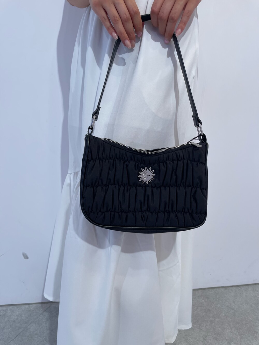 ホワイト系のワンピース、ブラック系のハンドバッグ、ブラック系のサンダルを着用したレディースの夏コーディネートの6枚目の写真