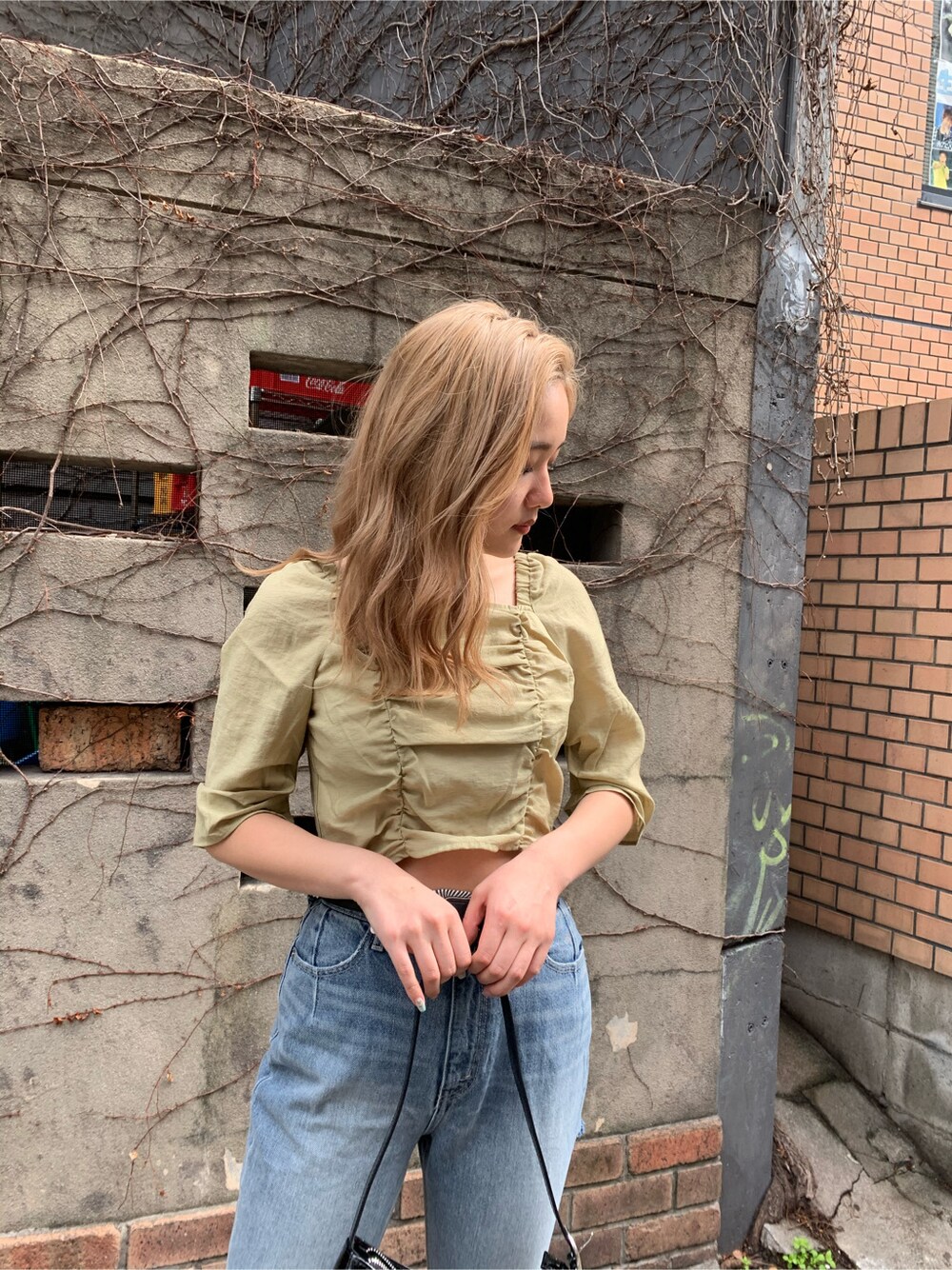 ブルー系のデニムパンツ、グリーン系のシャツ/ブラウス、ブラック系のショルダーバッグを着用したレディースの春コーディネートの3枚目の写真