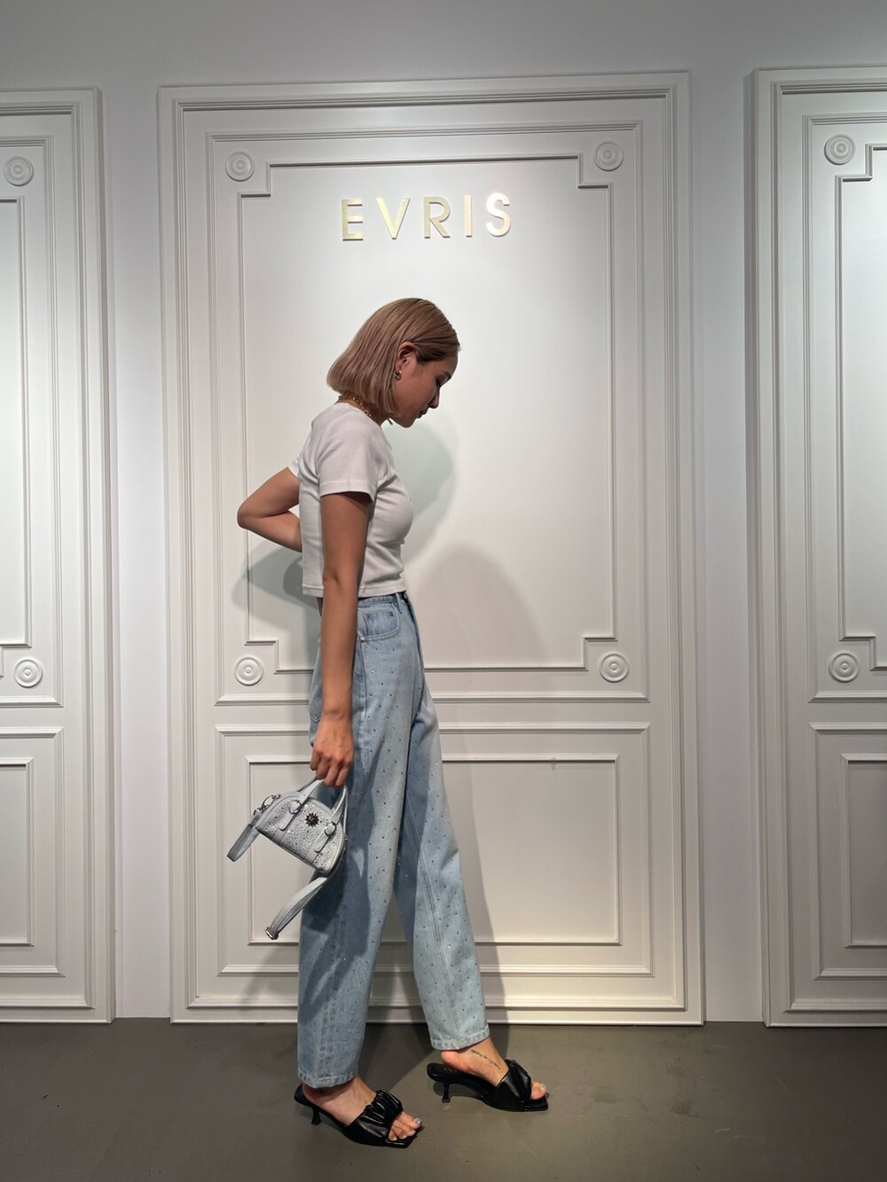 ブルー系のデニムパンツ、ブラック系のサンダル、ホワイト系のTシャツ/カットソーを着用したレディースの夏コーディネートの3枚目の写真