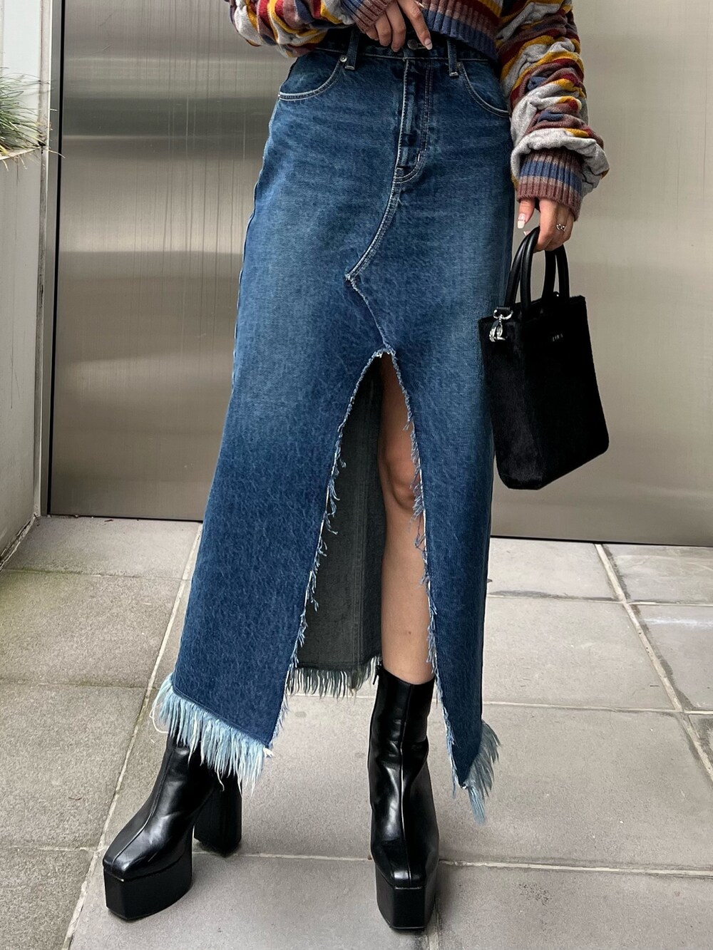 ブルー系のデニムスカート、ブラック系のブーツ、ブラック系のニット/セーターを着用したレディースの秋コーディネートの6枚目の写真