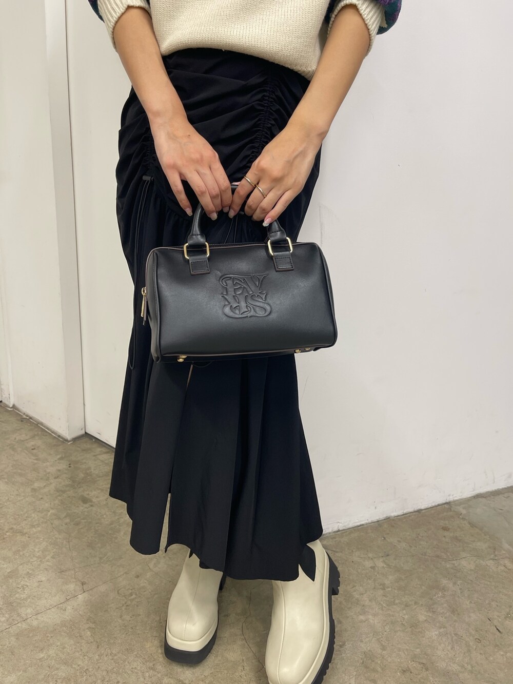 ブラック系のスカート、ホワイト系のブーツ、イエロー系のニット/セーターを着用したレディースの秋コーディネートの10枚目の写真