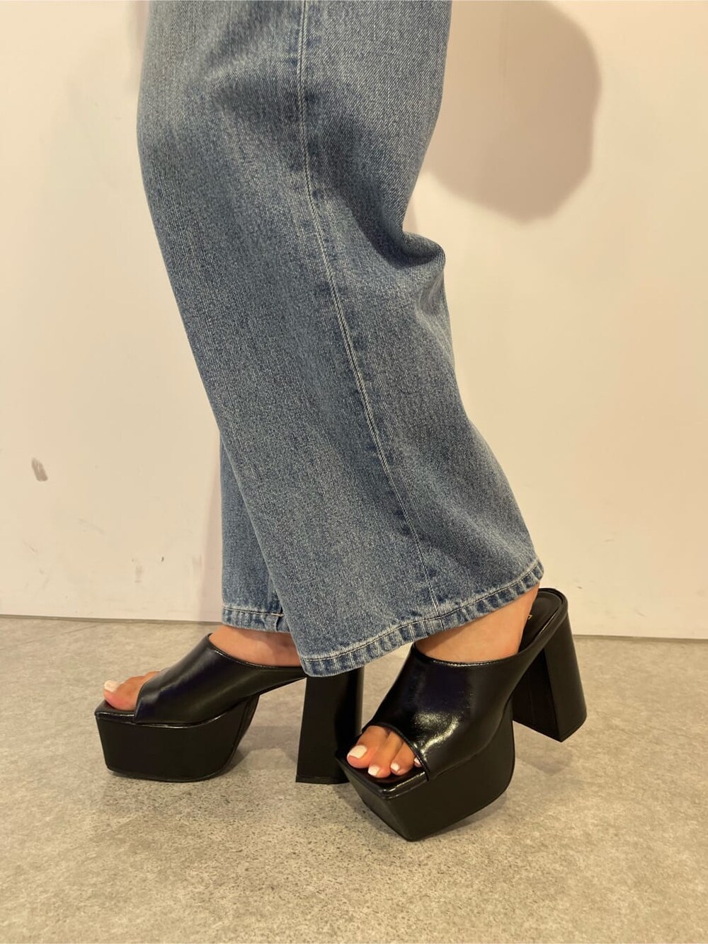 ブラック系のサンダル、ブラック系のボストンバッグ、ブルー系のデニムパンツを着用したレディースの夏コーディネートの10枚目の写真