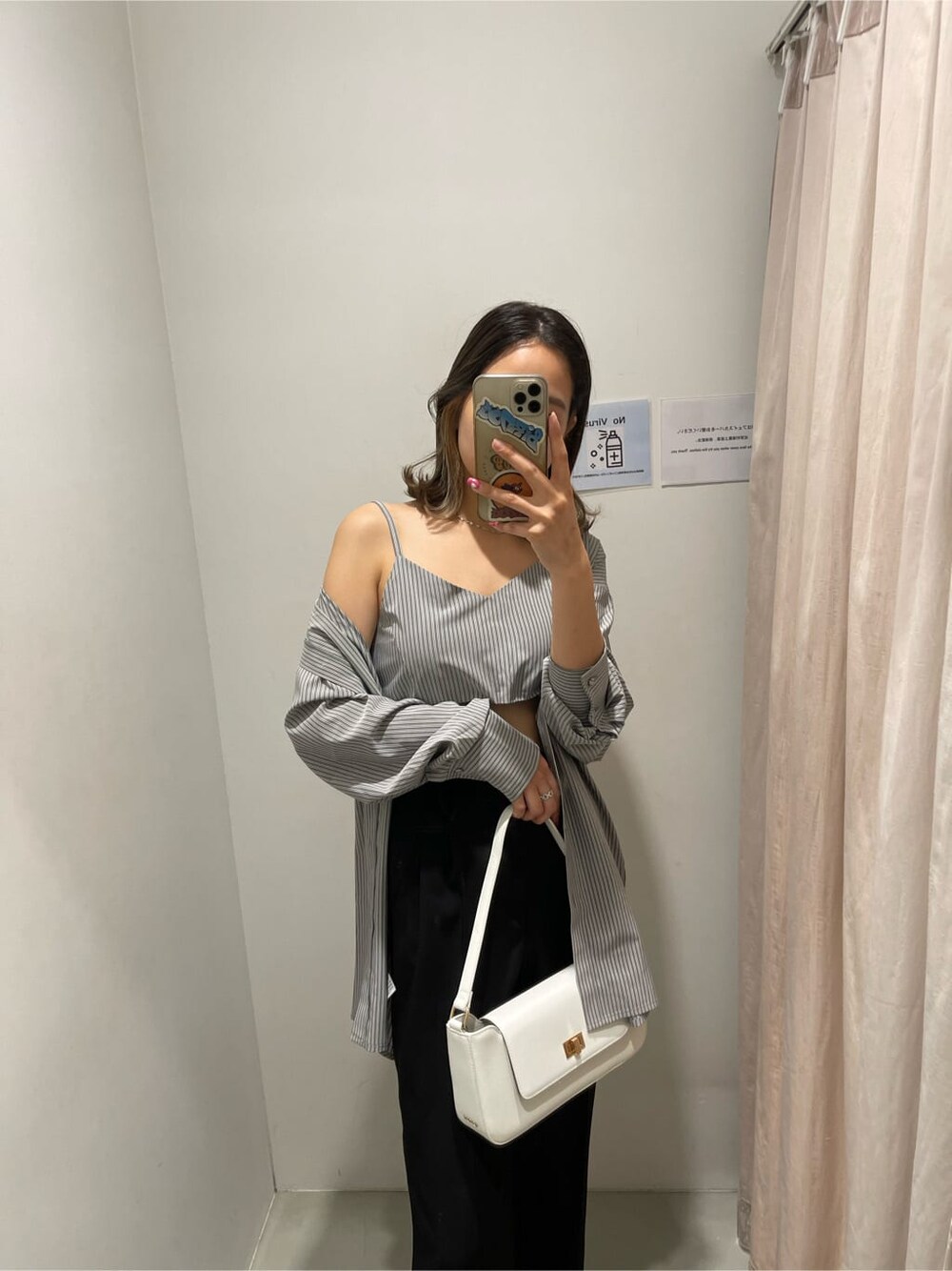 ブラック系のスラックス、ブラック系のワンピース、ホワイト系のショルダーバッグを着用したレディースの春コーディネートの3枚目の写真