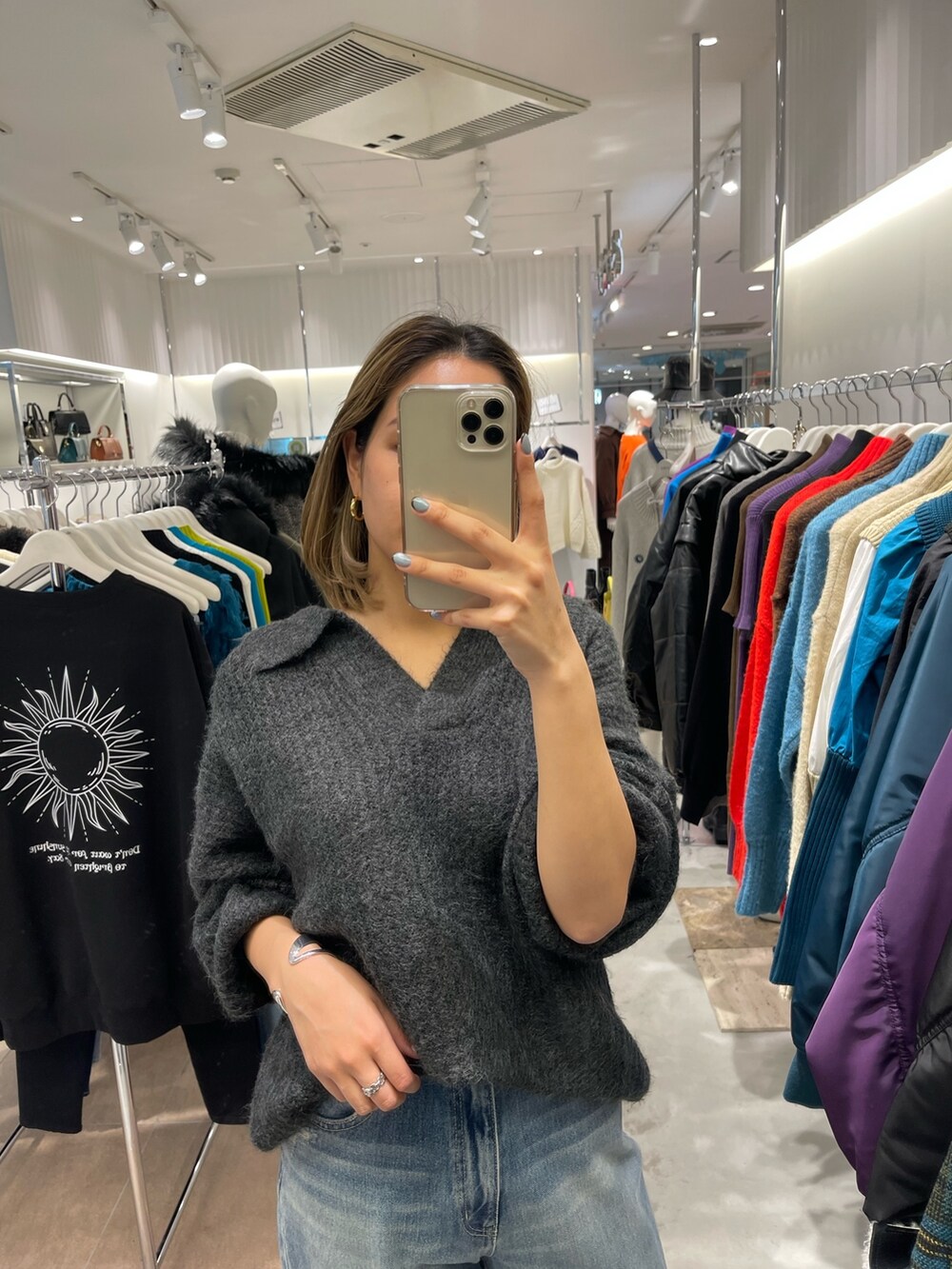 グレー系のニット/セーター、ブラック系のブーツ、ブルー系のデニムパンツを着用したレディースの秋コーディネートの4枚目の写真