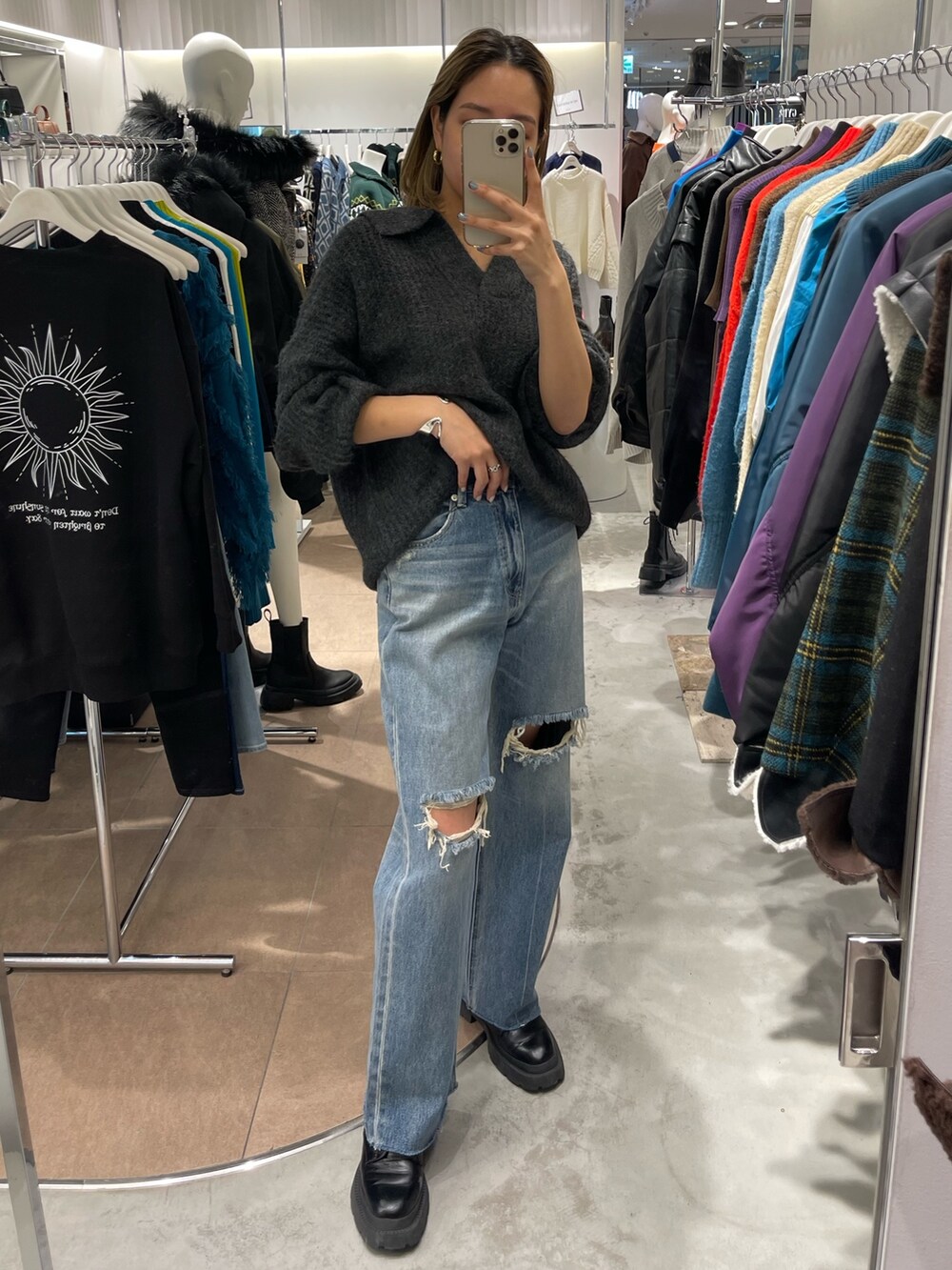 グレー系のニット/セーター、ブラック系のブーツ、ブルー系のデニムパンツを着用したレディースの秋コーディネートの3枚目の写真