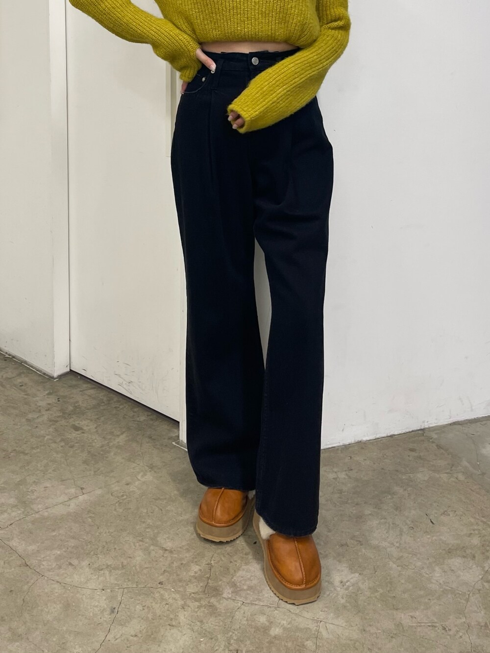 イエロー系のニット/セーター、ブラック系のデニムパンツ、ベージュ系のスリッポンを着用したレディースの秋コーディネートの6枚目の写真