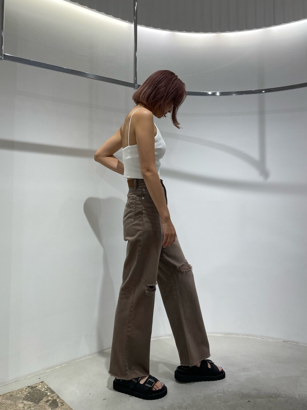 ブラック系のサンダル、ブラウン系のデニムパンツ、ホワイト系のキャミソールを着用したレディースの夏コーディネートの4枚目の写真